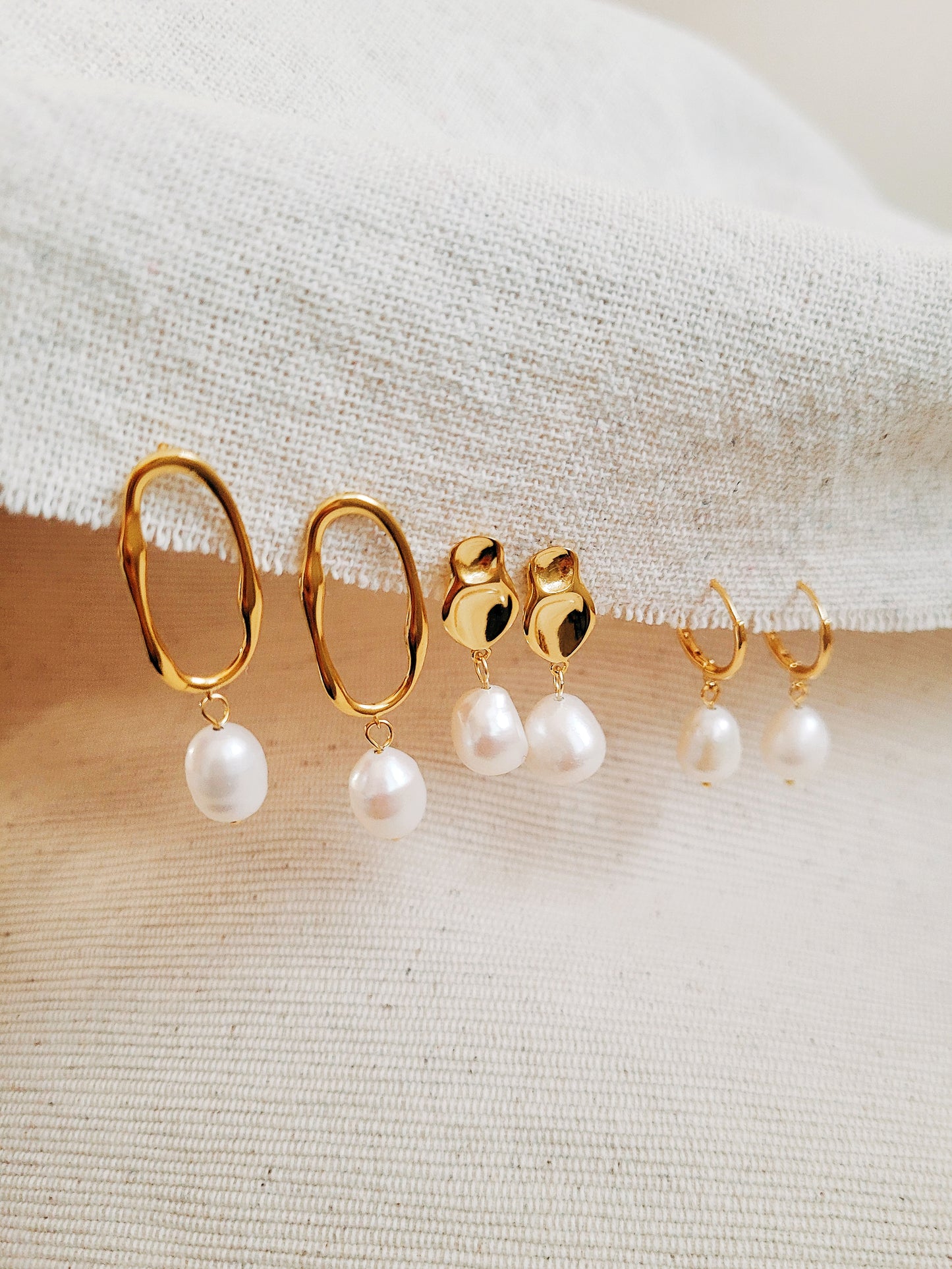 Freshwater pearl and gold hoop earrings elegantly laid out on a neutral fabric, perfect for gifting.