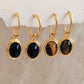 Close-up of gold vermeil dangle earrings with an oval black onyx gemstone or tiger's eye gemstone, minimalist and elegant style.