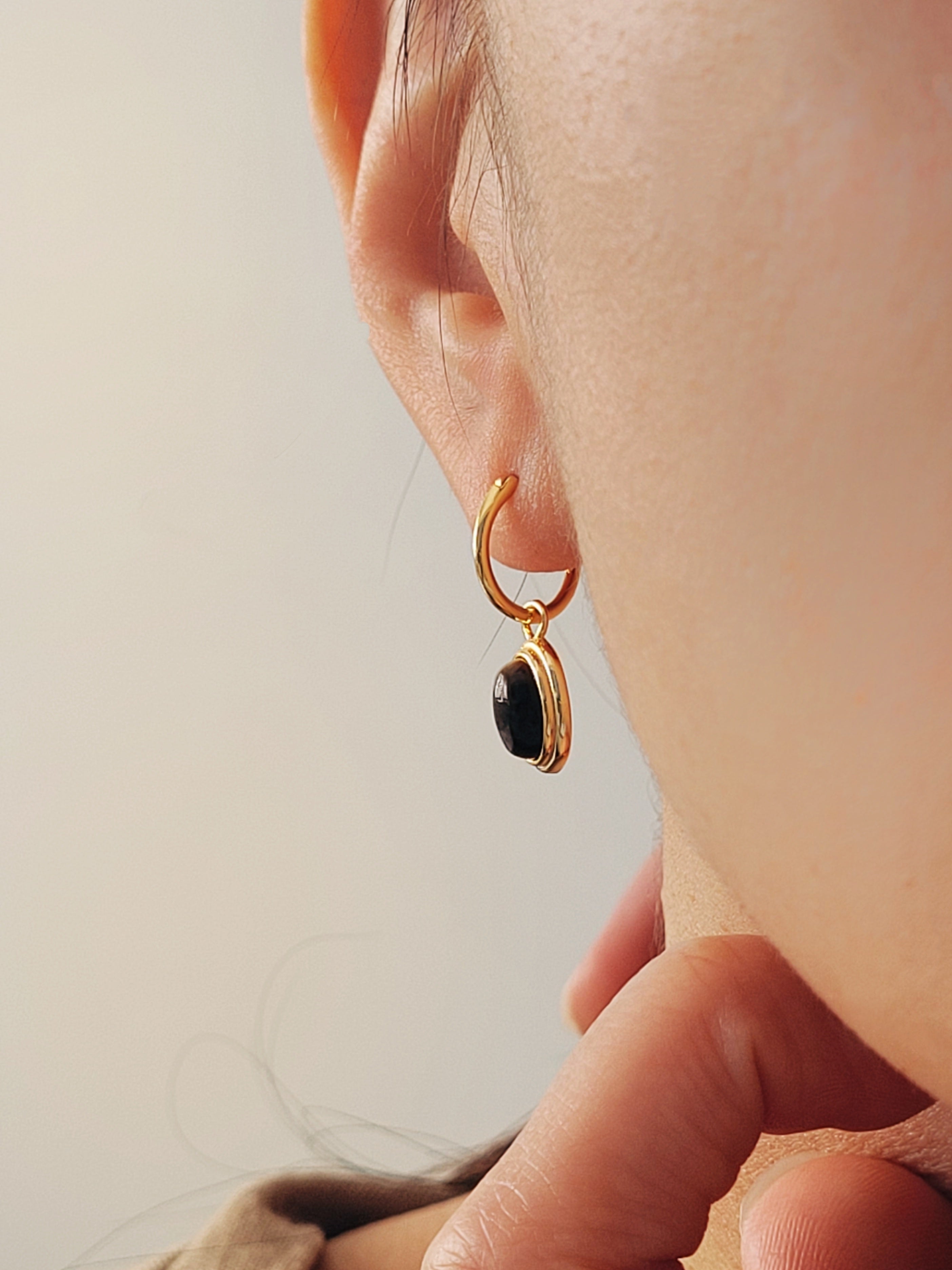 Side view of a woman wearing tiger's eye dangle earring in minimalist elegance style