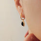Side view of a woman wearing tiger's eye dangle earring in minimalist elegance style