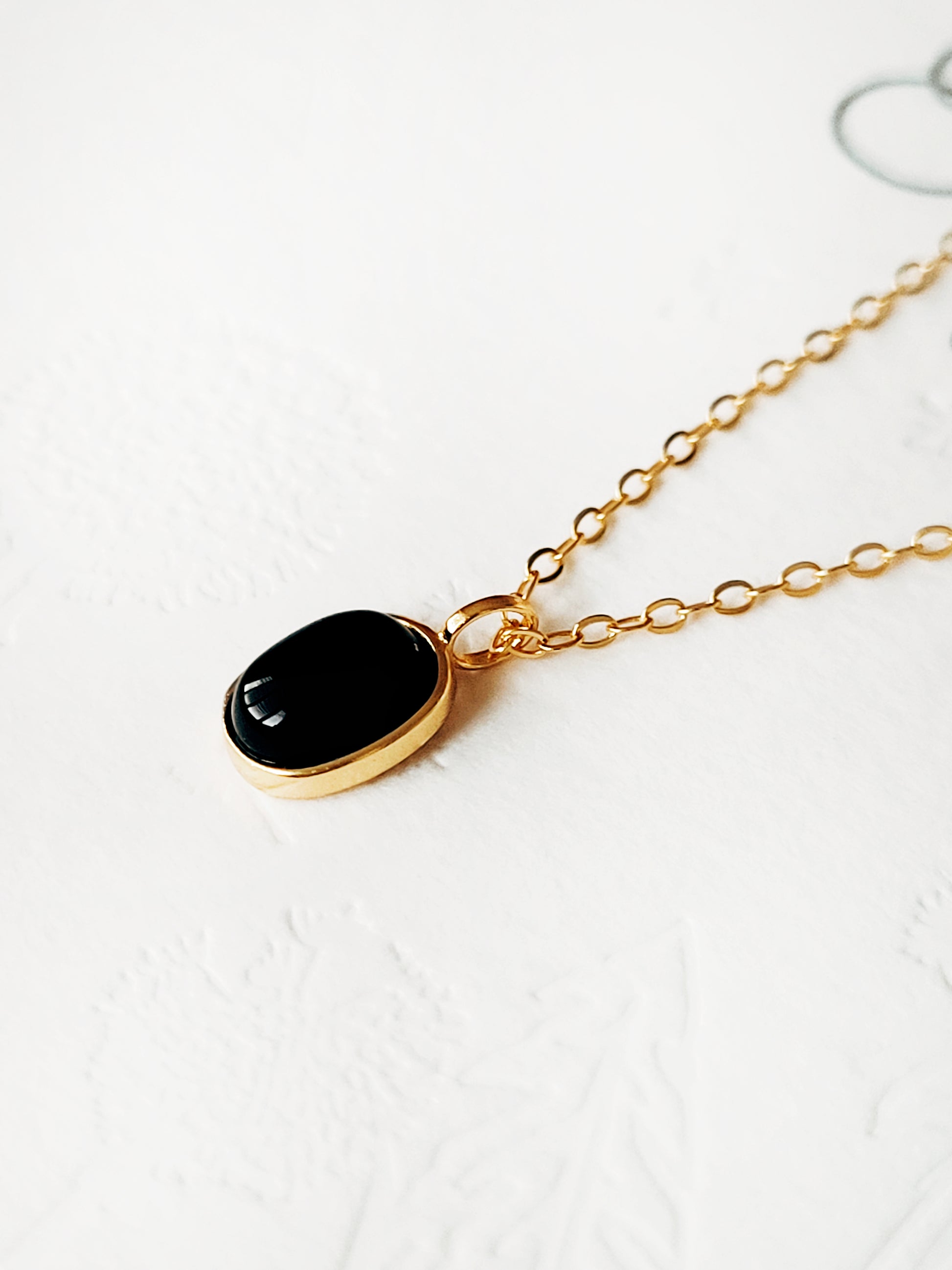 Minimalist black onyx pendant necklace with a gold-plated frame on a delicate chain.