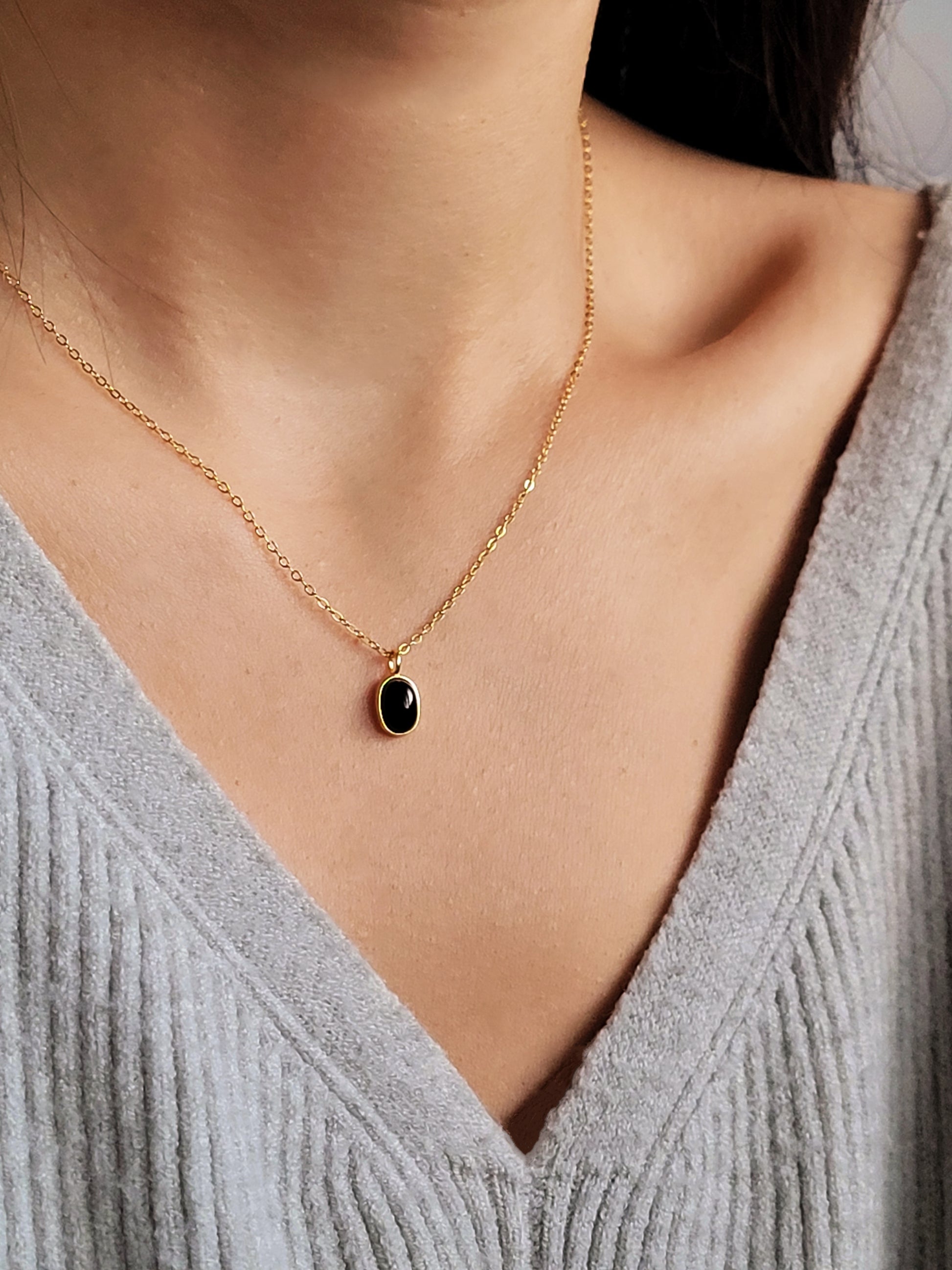 Minimalist black onyx pendant necklace with a gold-plated frame on a delicate chain.