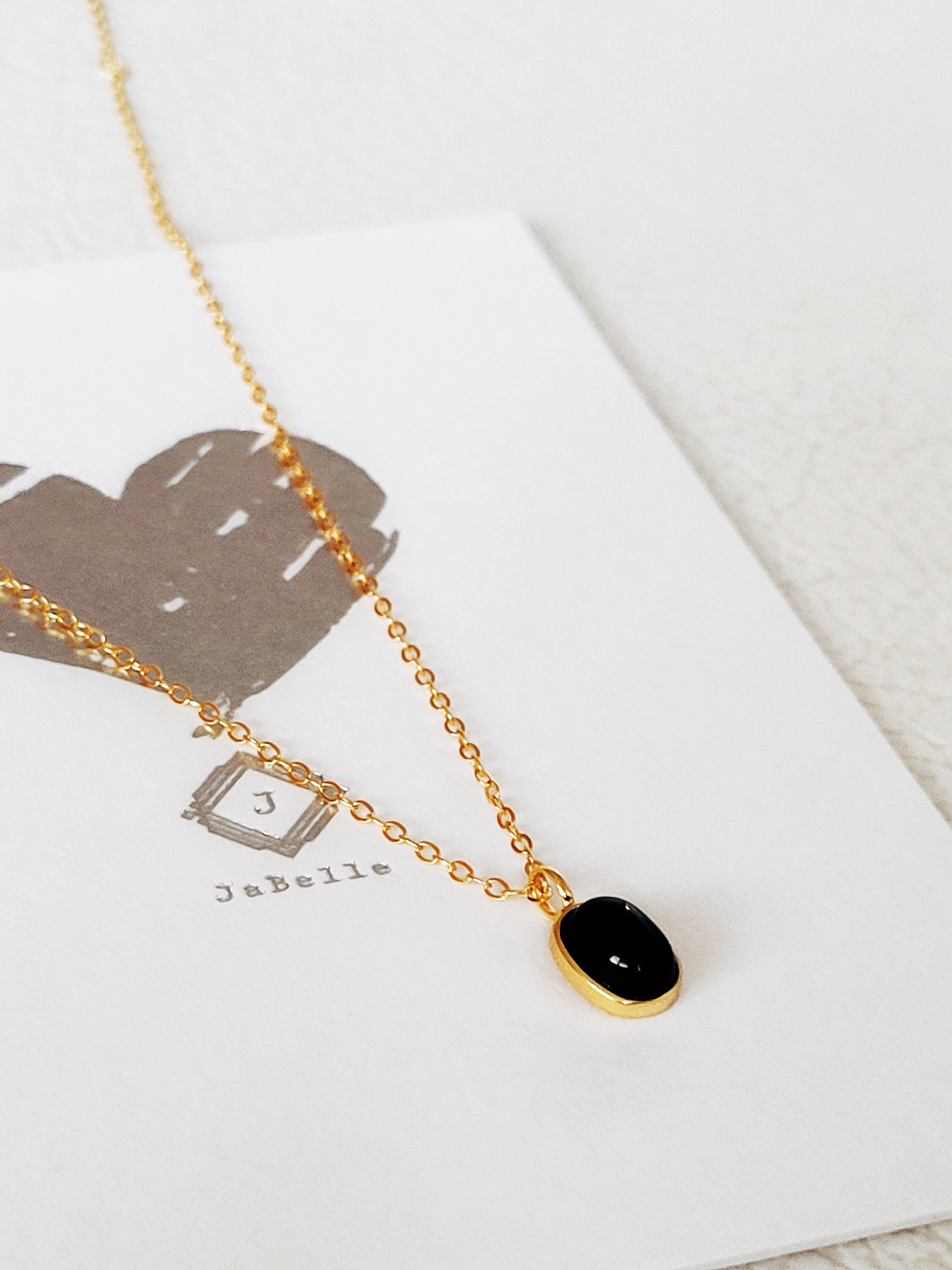 Minimalist black onyx pendant necklace with a gold-plated frame on a delicate chain.