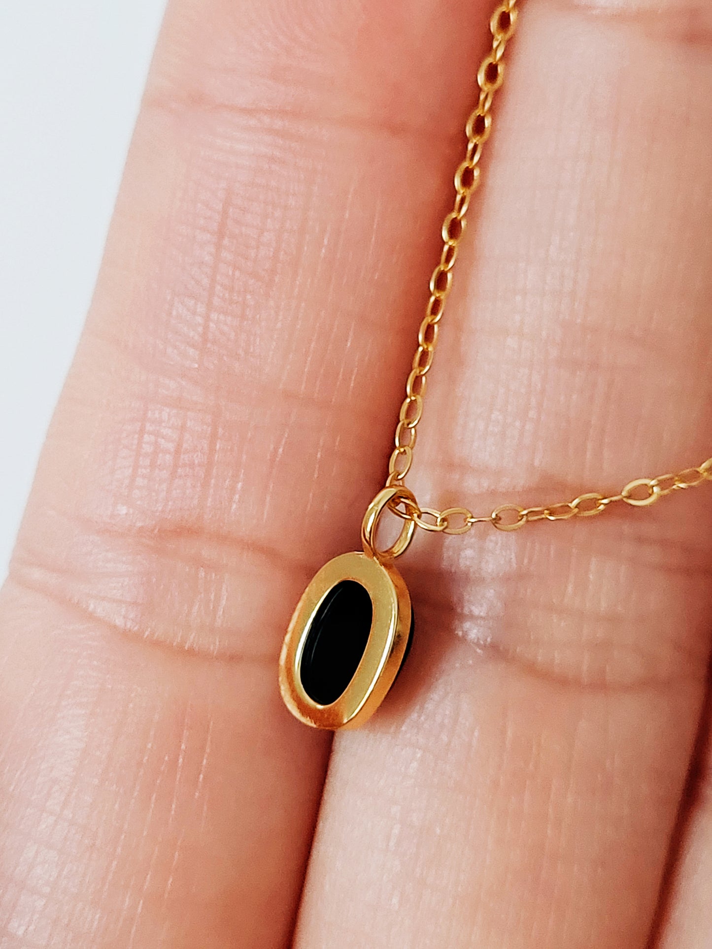 Minimalist black onyx pendant necklace with a gold-plated frame on a delicate chain.