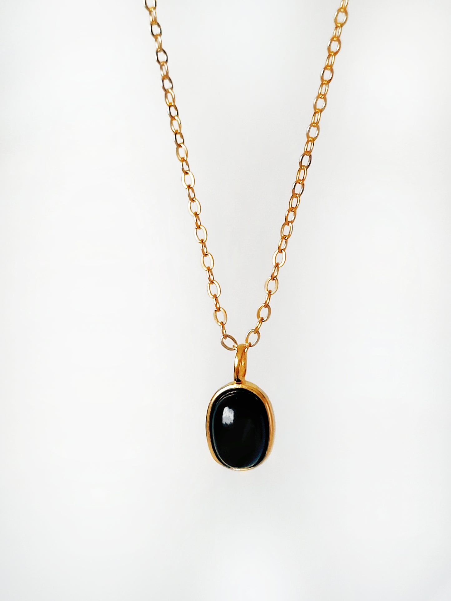 Minimalist black onyx pendant necklace with a gold-plated frame on a delicate chain.