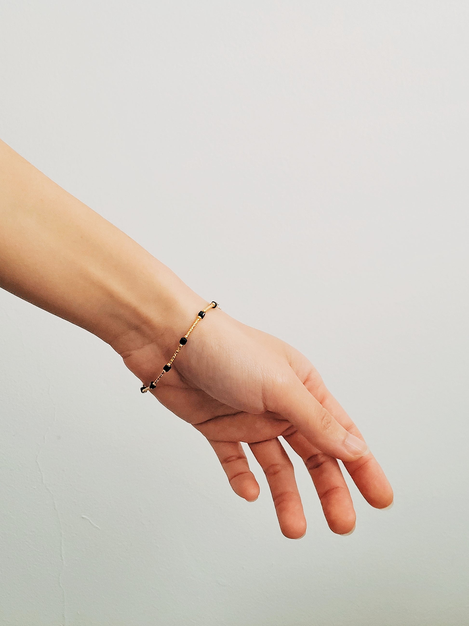 Close-up of a vintage-inspired Black tourmaline Bracelet featuring faceted black beads and textured gold vermeil bars on a wrist. Delicate and dainty bracelet gift for her.