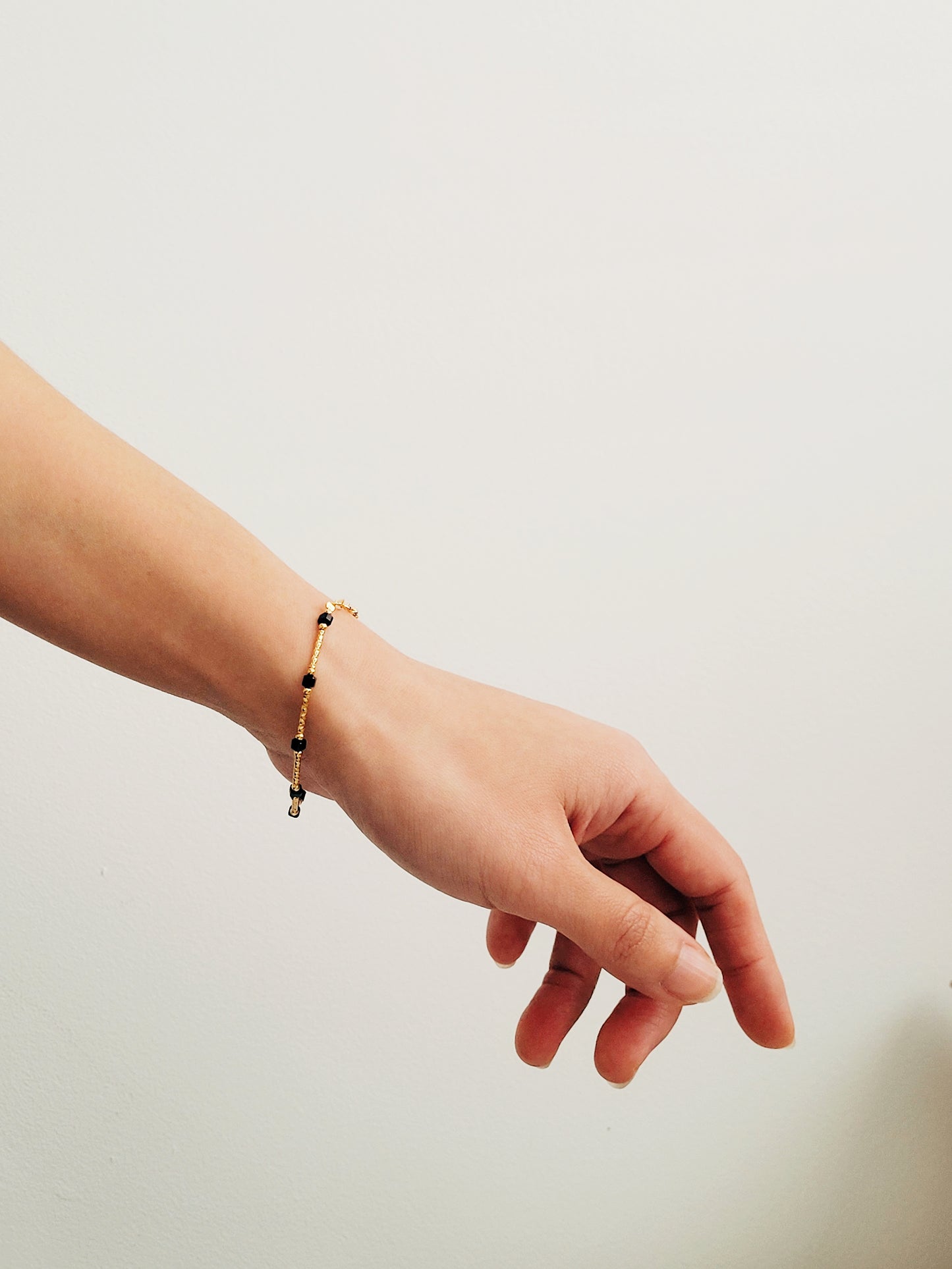 Close-up of a vintage-inspired Black tourmaline Bracelet featuring faceted black beads and textured gold vermeil bars on a wrist. Delicate and dainty bracelet gift for her.