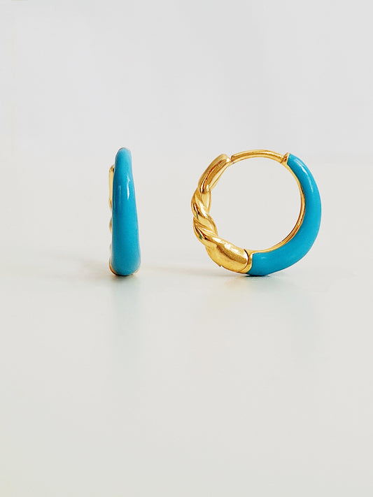 Close-up of bright blue enamel twisted hoop earrings on a white surface.