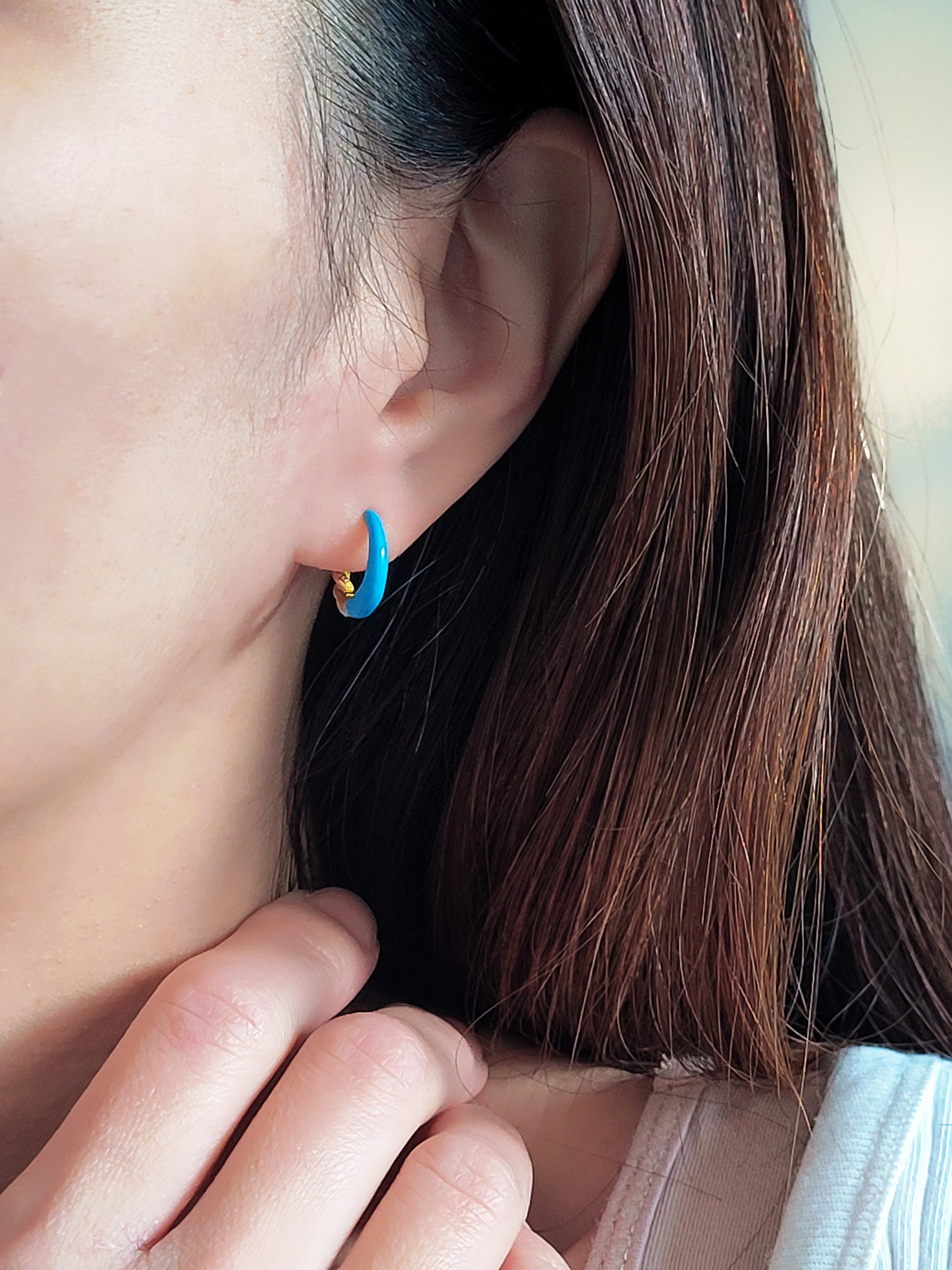 Close-up of bright blue enamel twisted hoop earrings on a white surface.