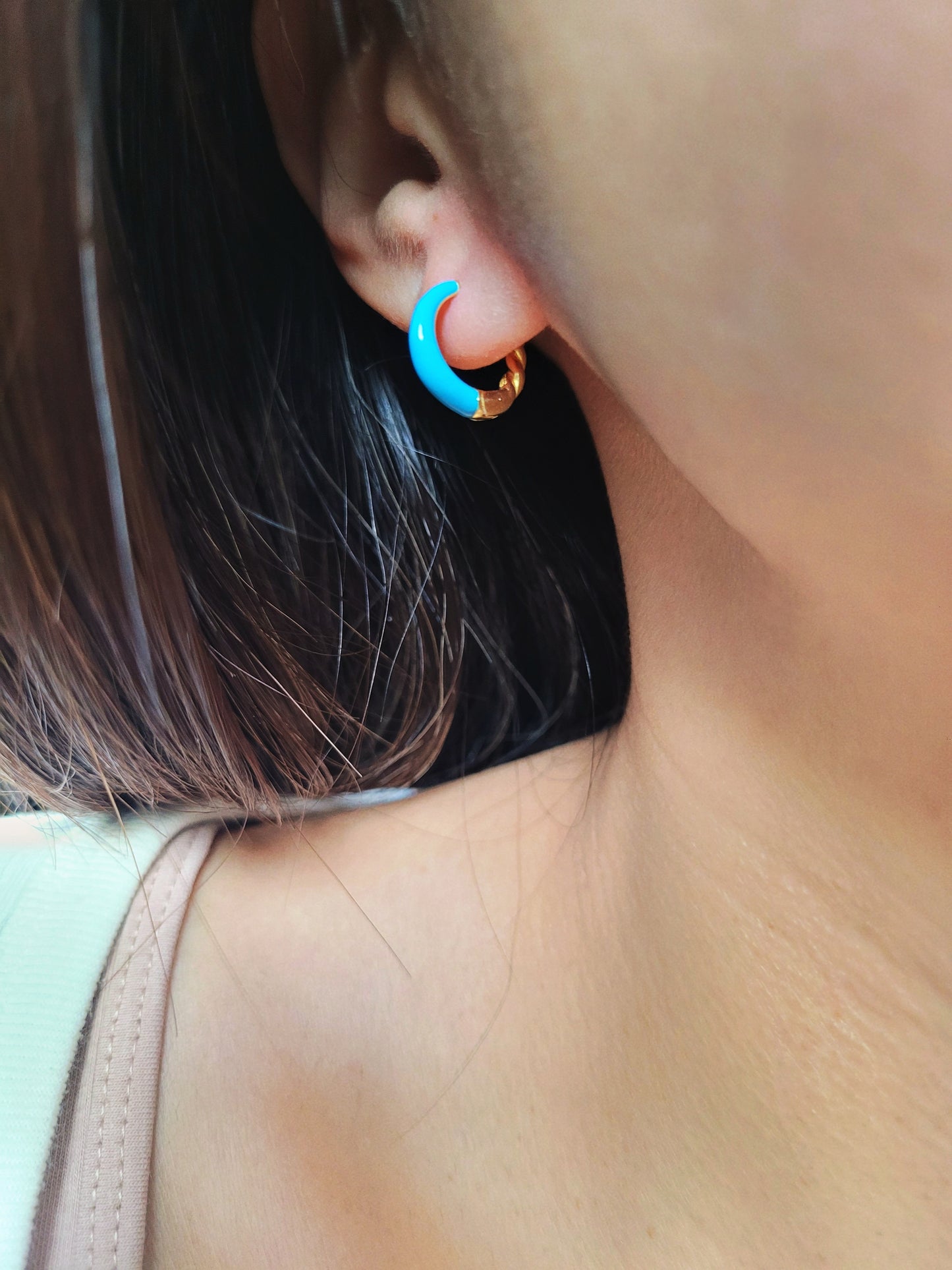 Close-up of bright blue enamel twisted hoop earrings on a white surface.