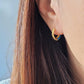 Close-up of bright blue enamel twisted hoop earrings on a white surface.
