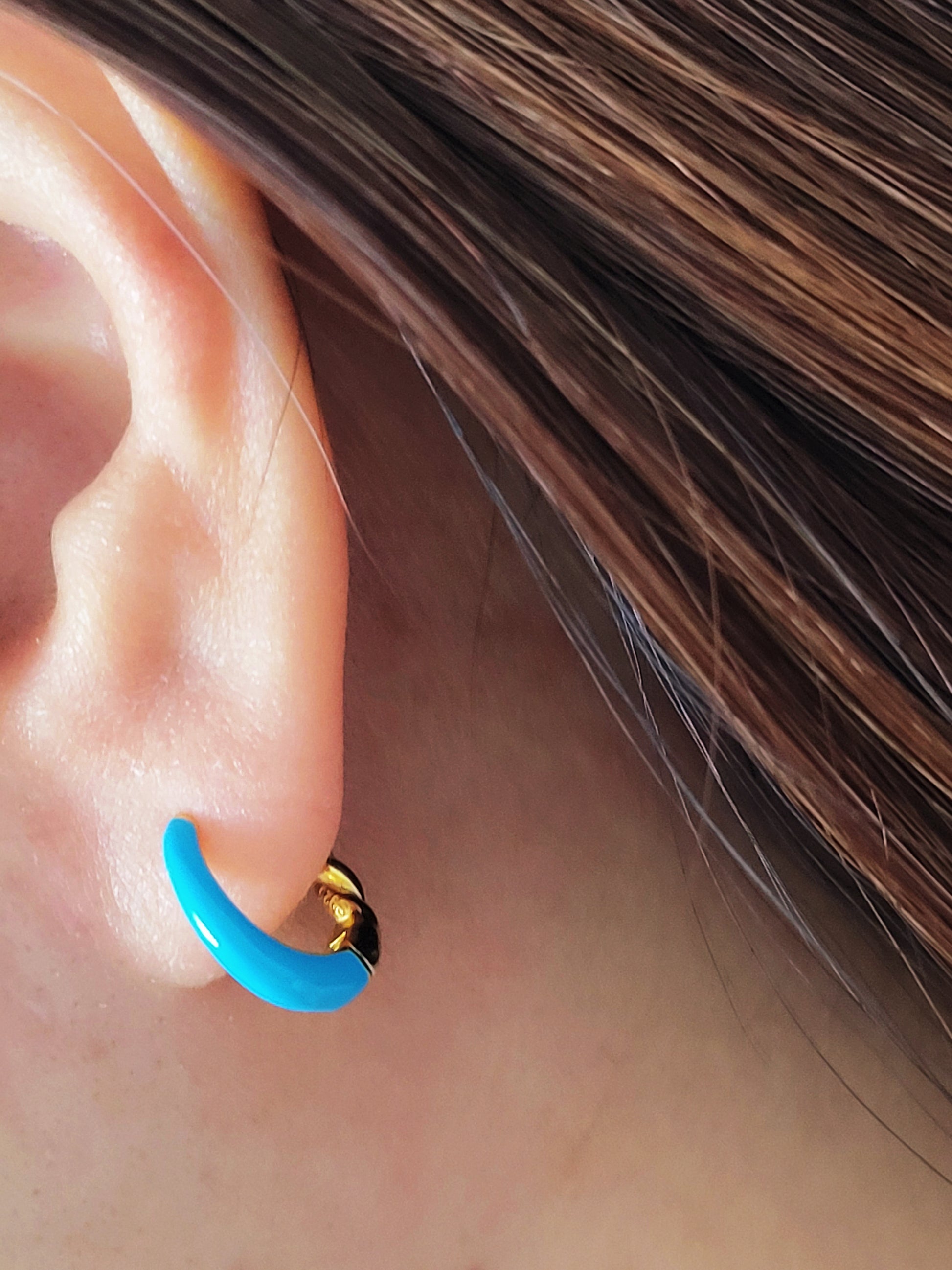 Close-up of bright blue enamel twisted hoop earrings on a white surface.