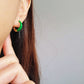 Close-up of bright blue enamel twisted hoop earrings on a white surface.