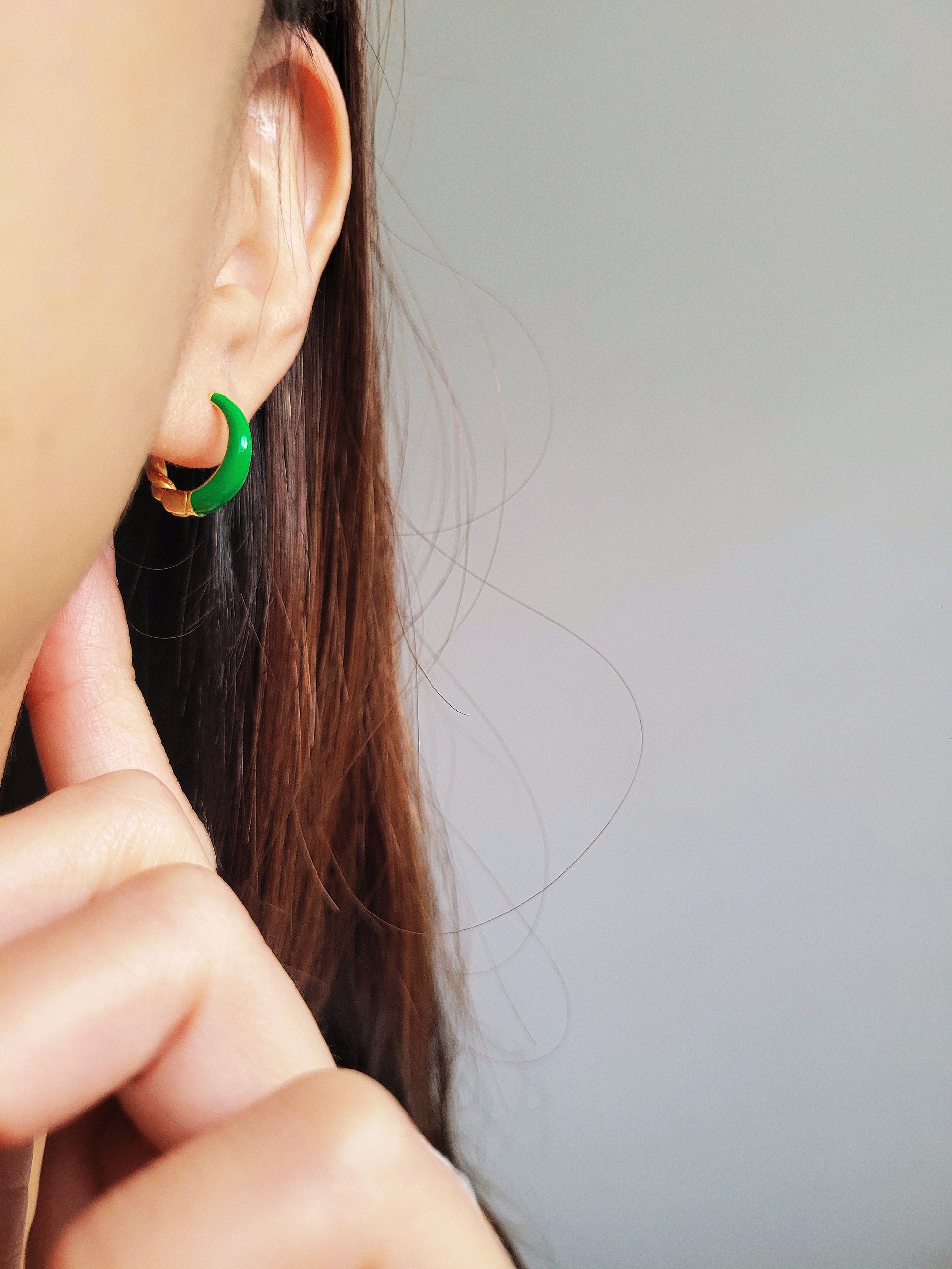 Close-up of bright blue enamel twisted hoop earrings on a white surface.