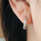 Dainty silver hoop earring with braided details worn by a woman.