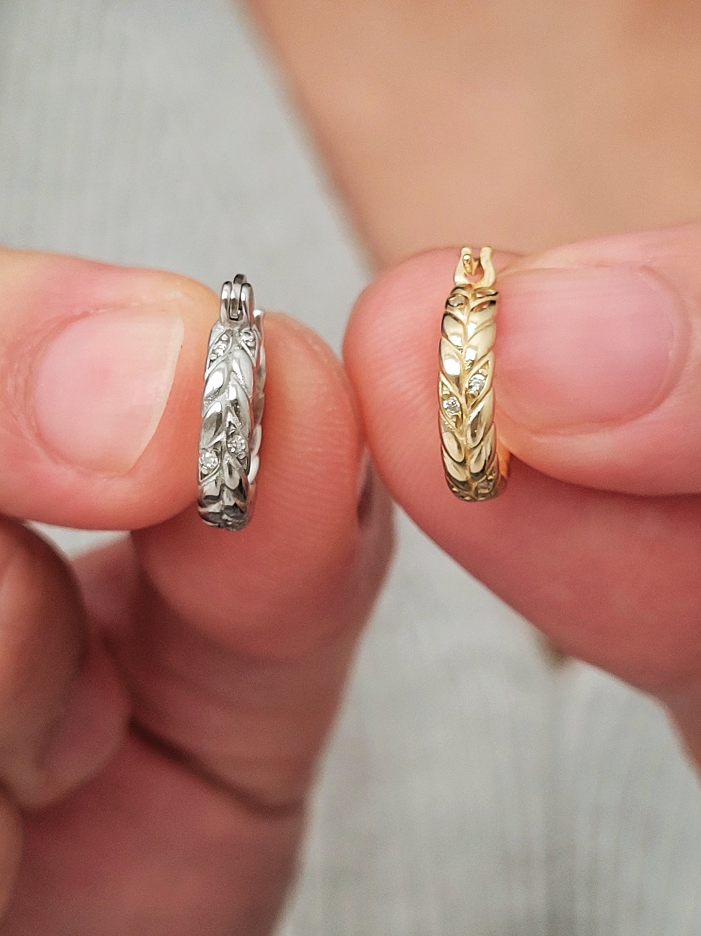 Minimalist gold and silver hoop earrings held by a woman