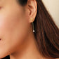 Dainty 18k gold vermeil butterfly stud earring with a delicate chain drop and sparkling pear-cut cubic zirconia stone worn on a model.