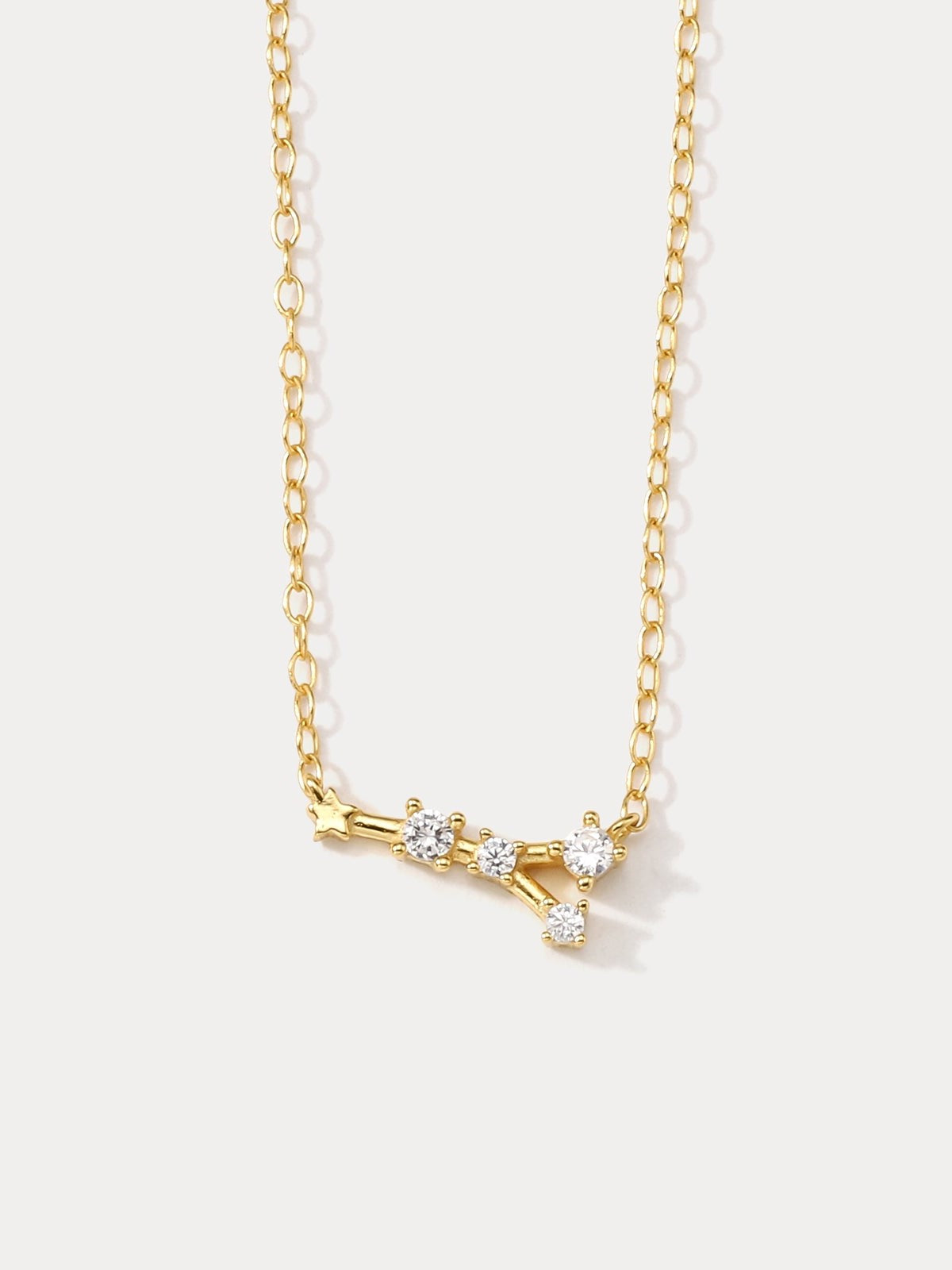 A dainty gold necklace with a pendant featuring a stylized Cancer zodiac constellation sign with sparkling zircons.