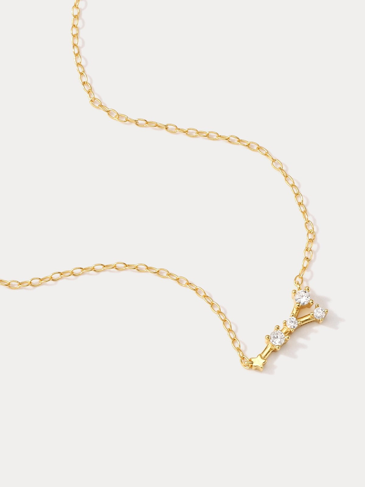 A dainty gold necklace with a pendant featuring a stylized Cancer zodiac constellation sign with sparkling zircons.