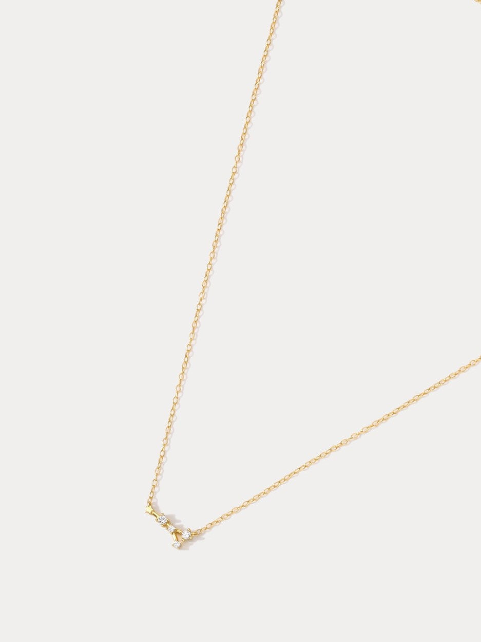 A dainty gold necklace with a pendant featuring a stylized Cancer zodiac constellation sign with sparkling zircons.