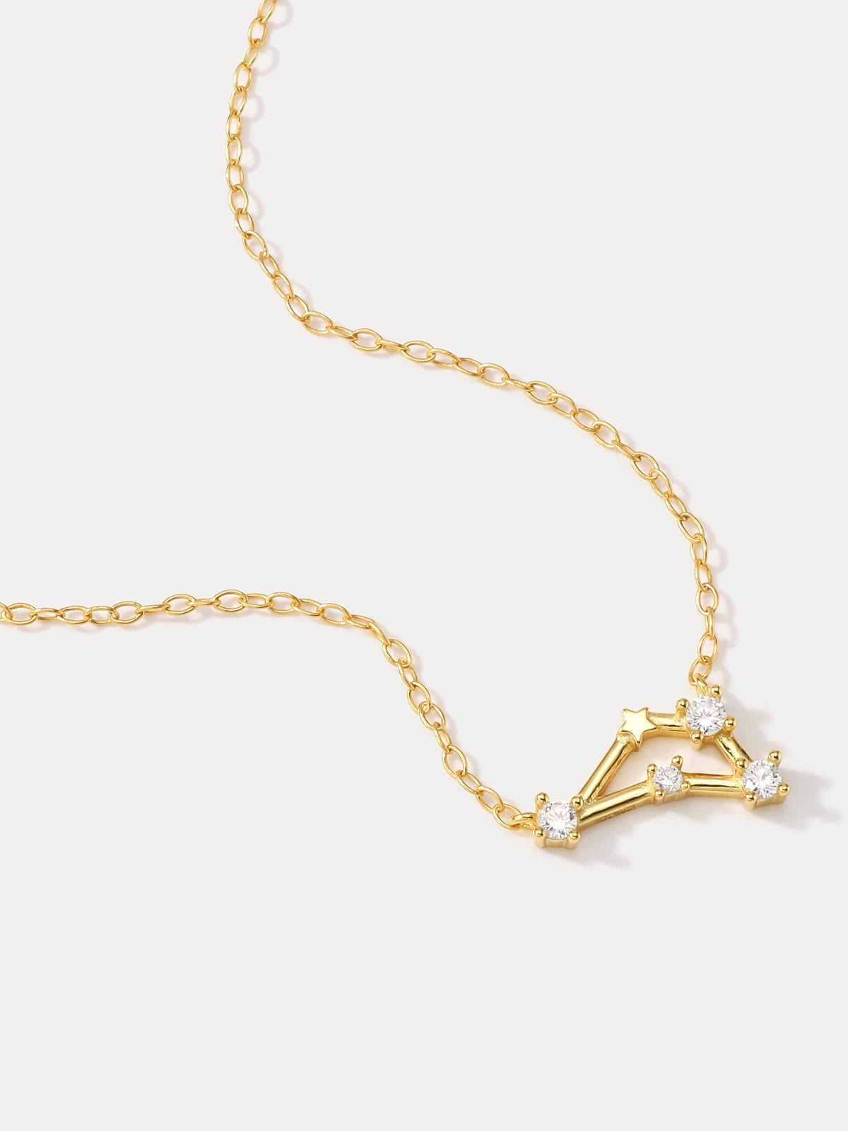 A dainty gold necklace with a pendant featuring a stylized Capricorn zodiac constellation sign with sparkling zircons.