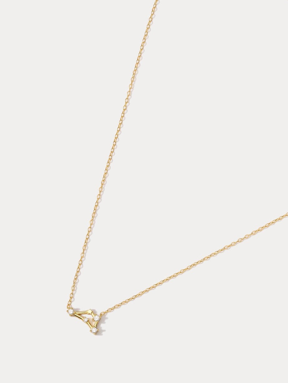 A dainty gold necklace with a pendant featuring a stylized Capricorn zodiac constellation sign with sparkling zircons.