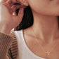 Close-up of a woman wearing a capricorn necklace and capricorn earring, showcasing the luxury aesthetic and pendant scale.
