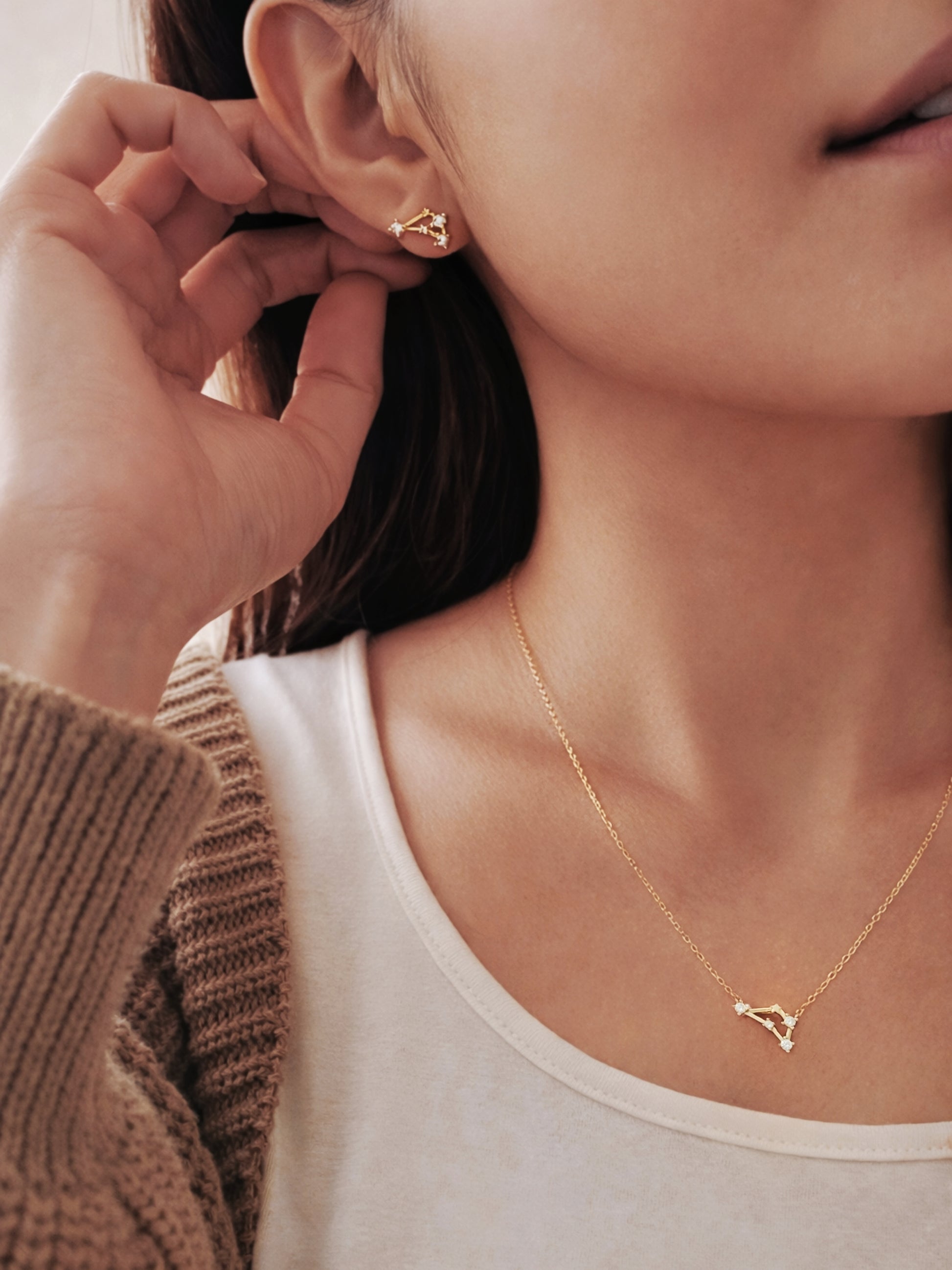 Close-up of a woman wearing a capricorn necklace and capricorn earring, showcasing the luxury aesthetic and pendant scale.