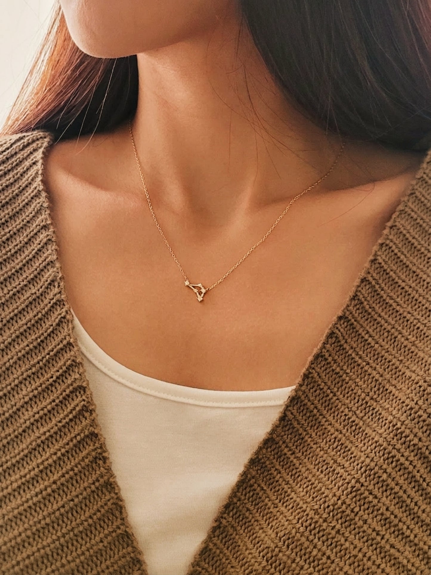 A delicate pendant necklace with Capricorn constellation sign worn by woman, crafted in gold plated sterling silver.