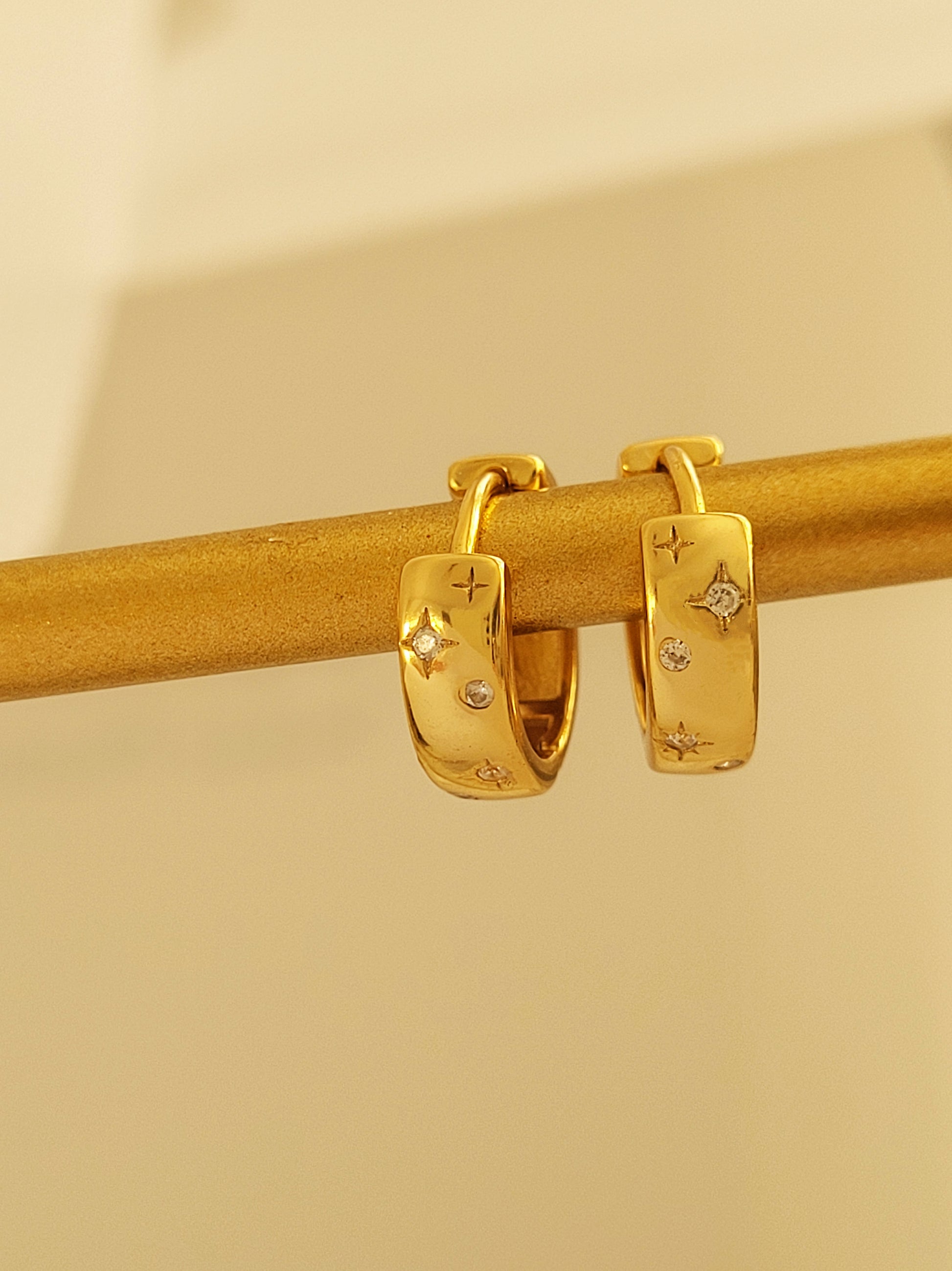 Close-up of minimalist huggie hoops with a celestial star design, perfect for everyday wear or gifting.