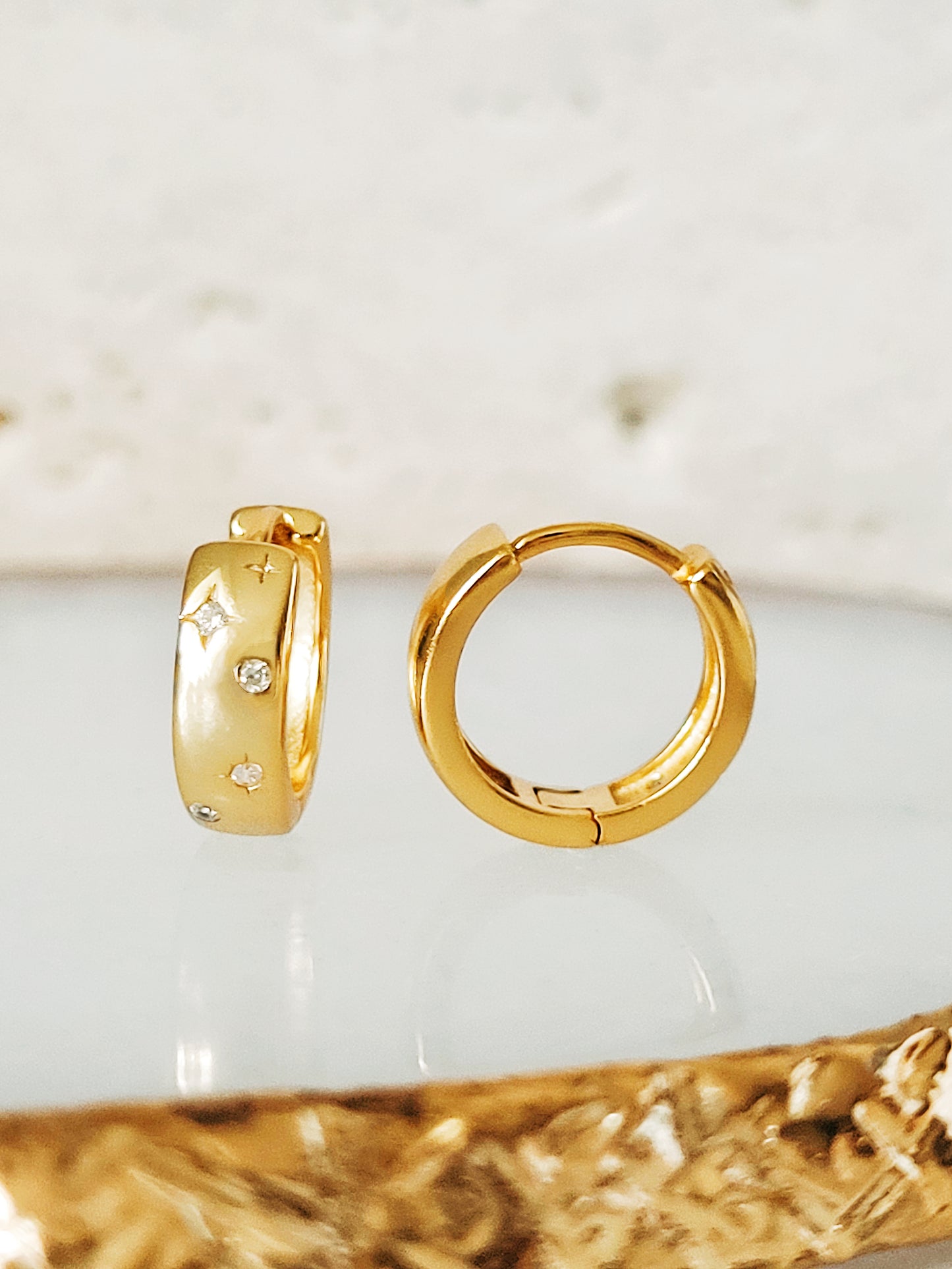 Close-up of minimalist huggie hoops with a celestial star design, perfect for everyday wear or gifting.