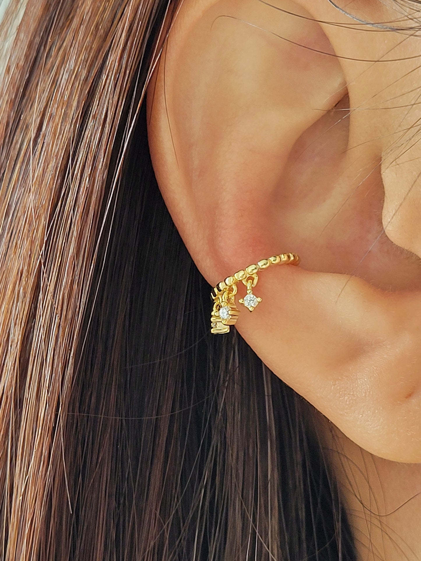 A chic gold-plated ear cuff with three delicate diamonds, blending luxury and style effortlessly.