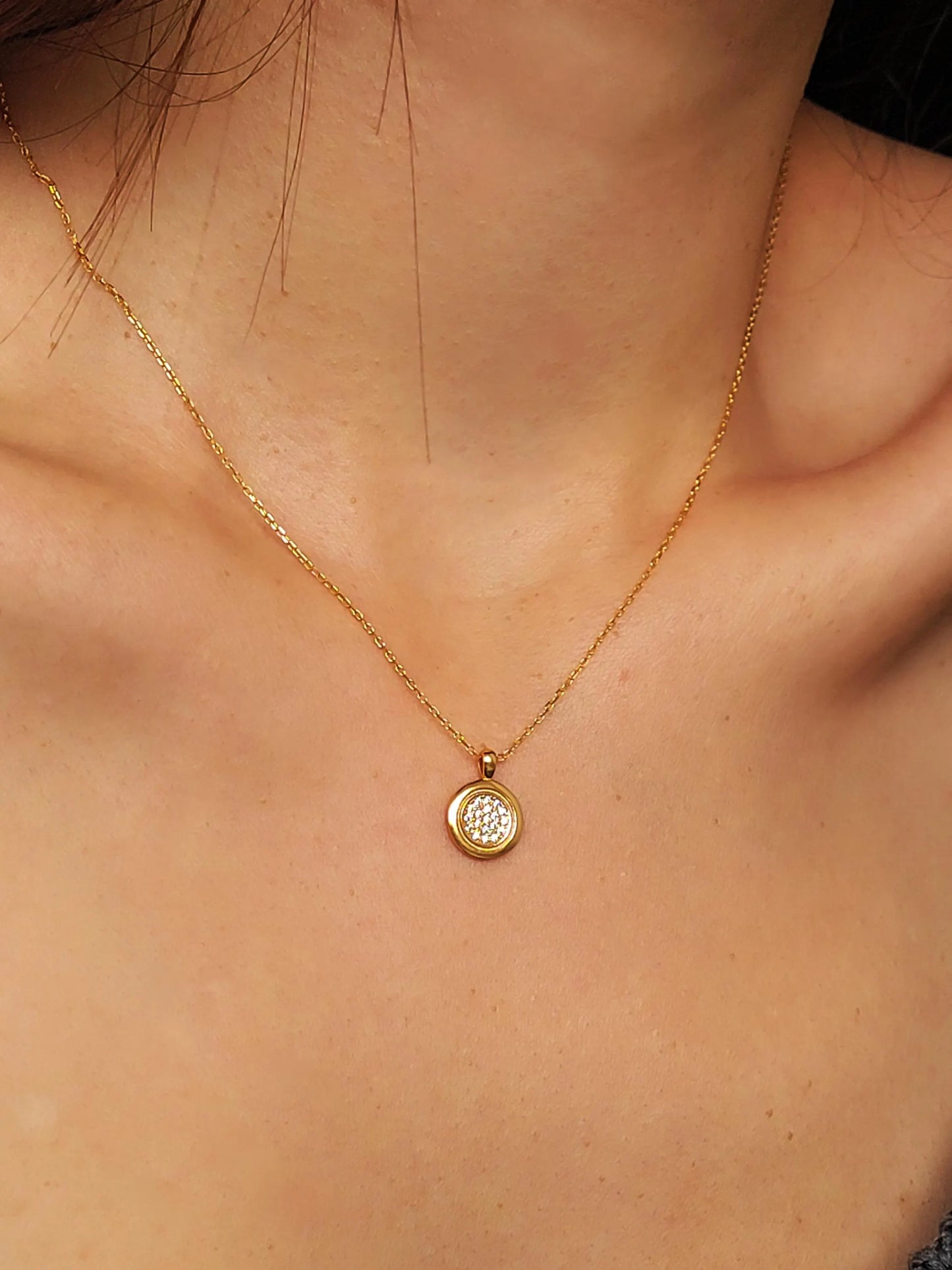 Elegant woman wearing a dainty 18K gold plated sterling silver circle pendant necklace with shimmering cubic zirconia accents, perfect for everyday wear and special occasions.