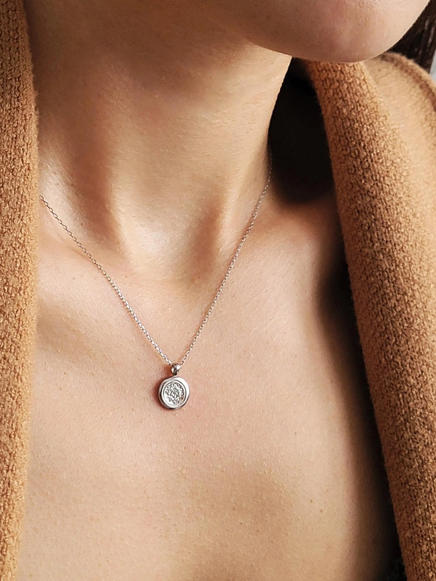 Elegant woman wearing a dainty sterling silver circle pendant necklace with shimmering cubic zirconia accents, perfect for everyday wear and special occasions.