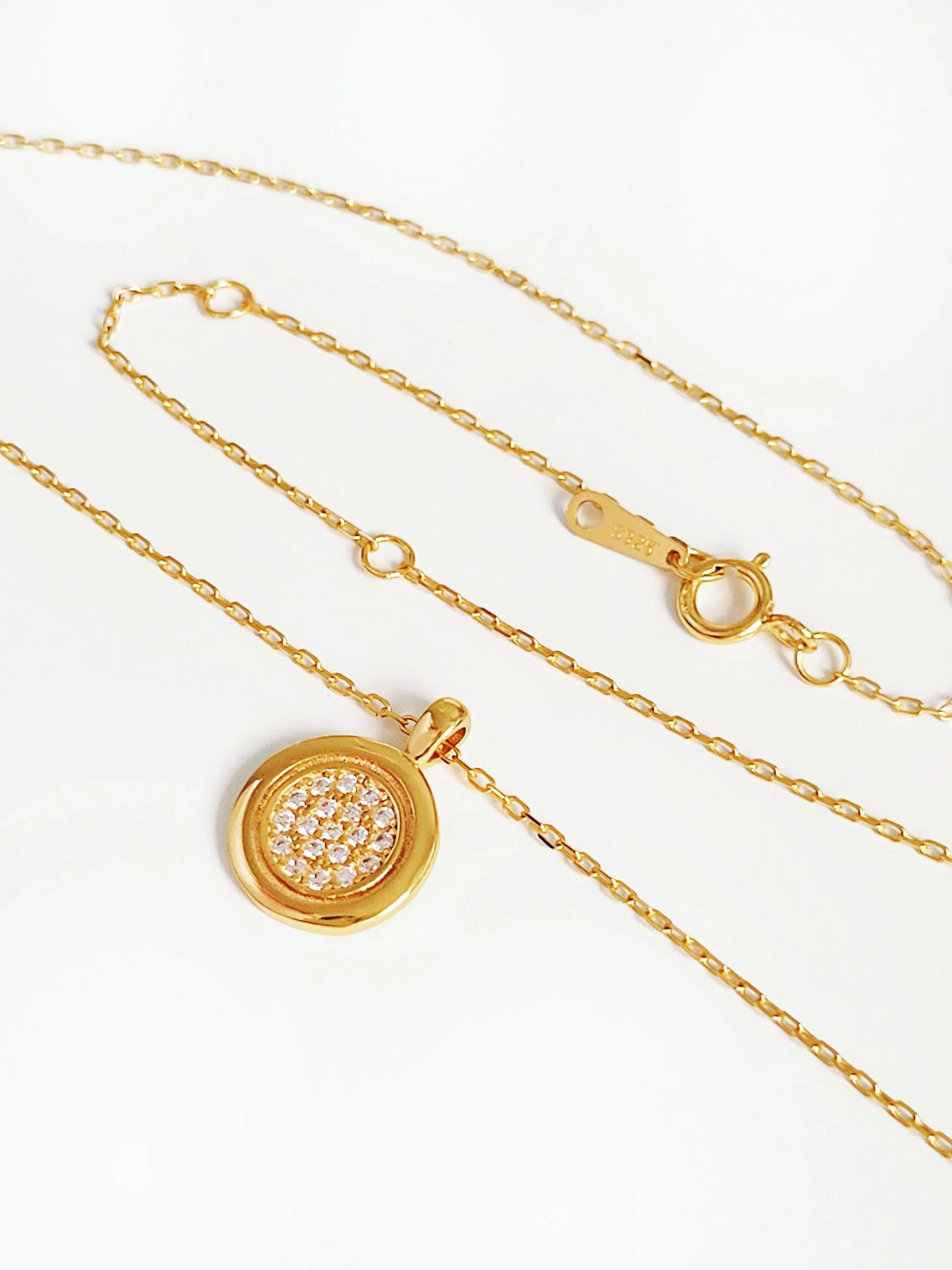 A dainty 18K gold plated sterling silver circle pendant necklace with shimmering cubic zirconia accents, perfect for everyday wear and special occasions.