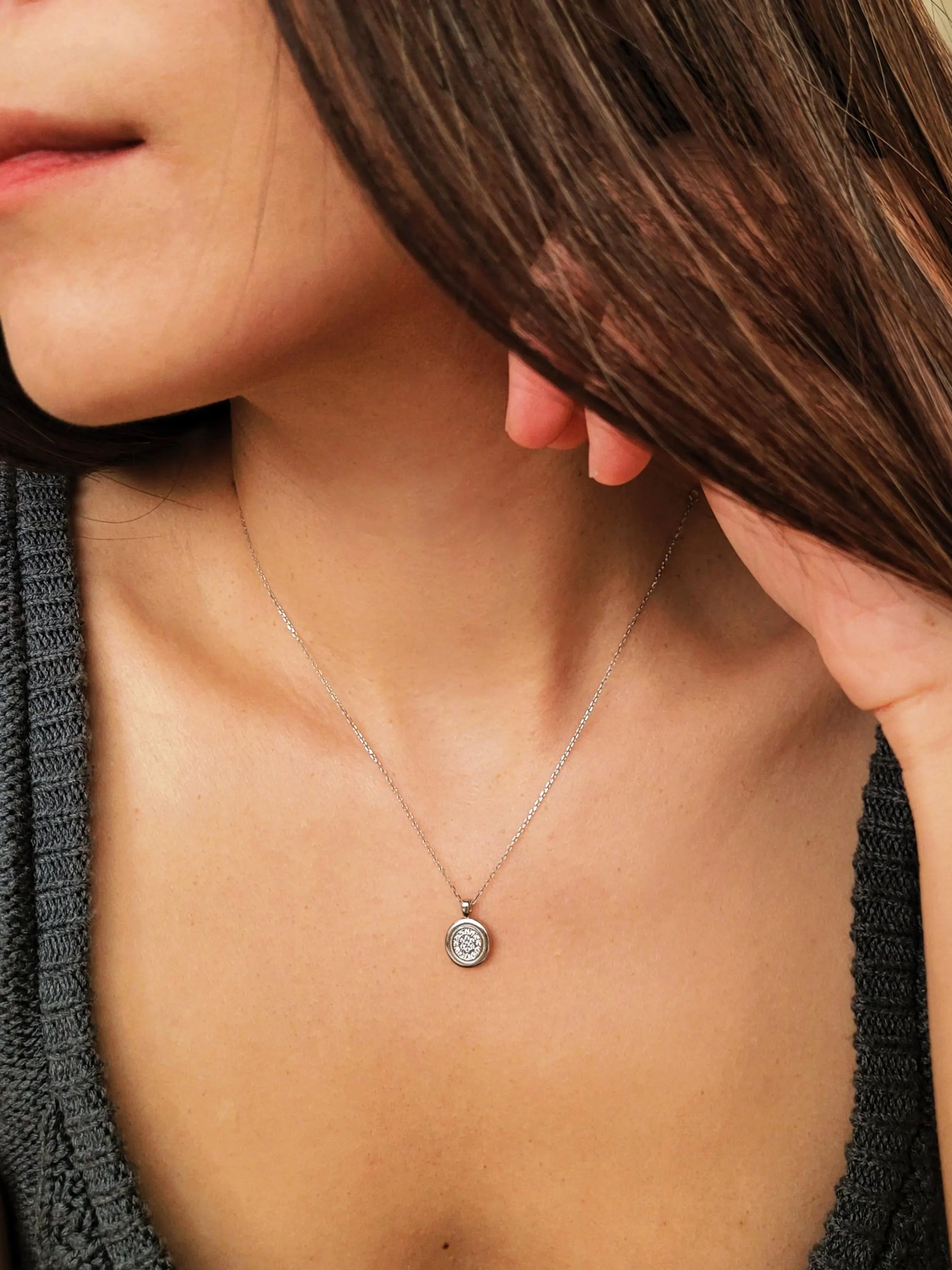 Elegant woman wearing a dainty sterling silver circle pendant necklace with shimmering cubic zirconia accents, perfect for everyday wear and special occasions.