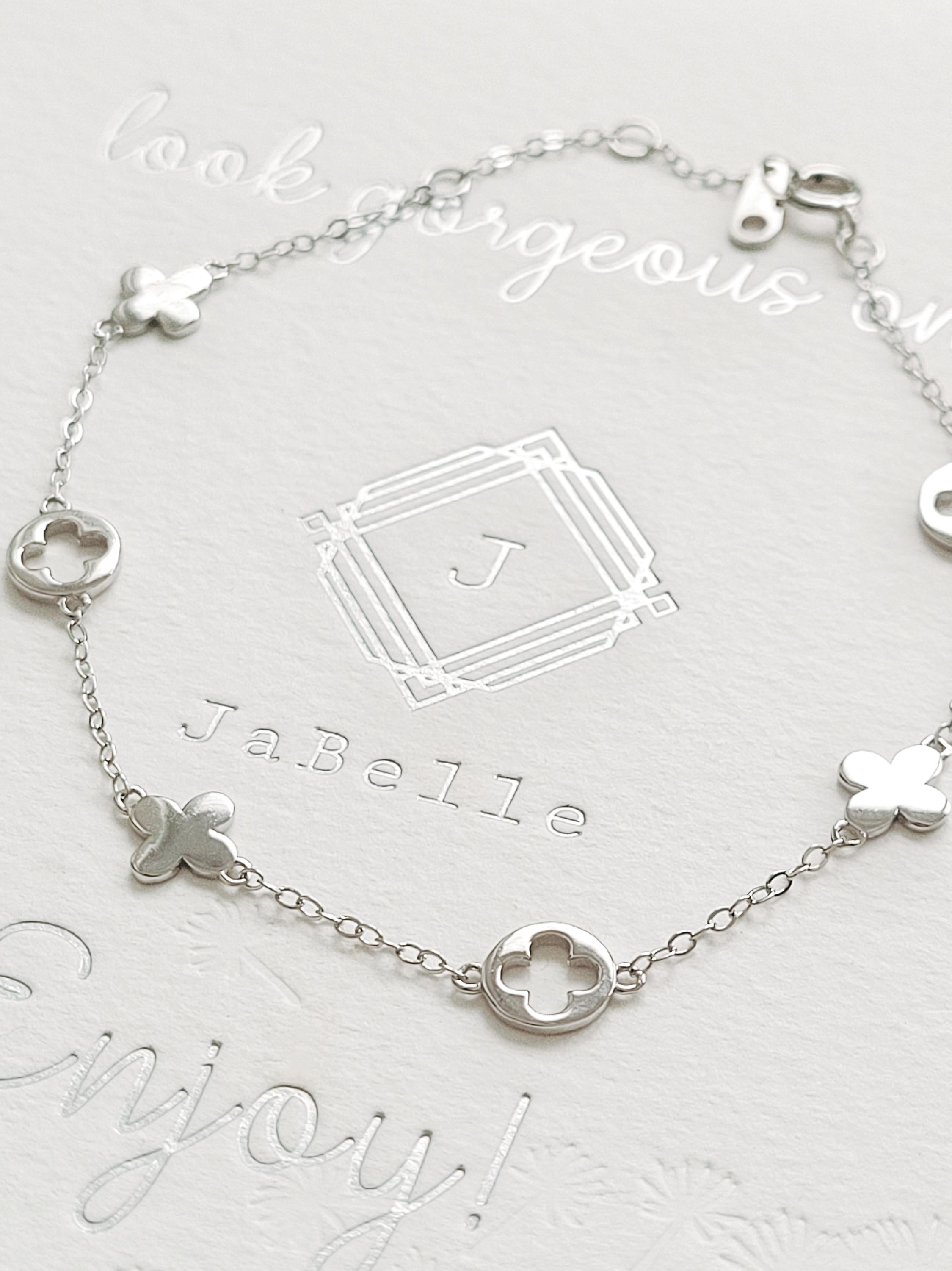 A dainty sterling silver bracelet with clover charms.