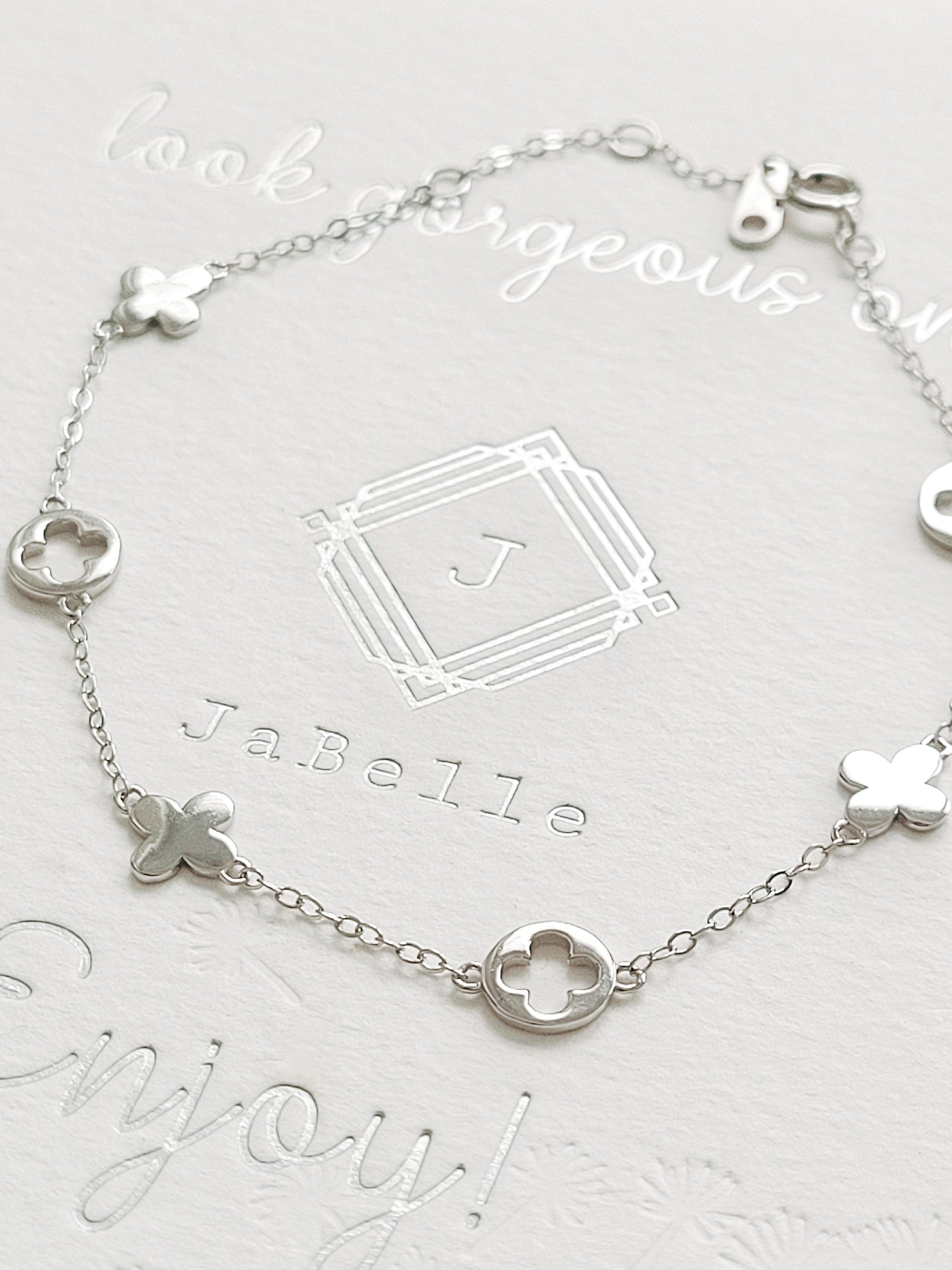A dainty sterling silver bracelet with van cleef clover charms.