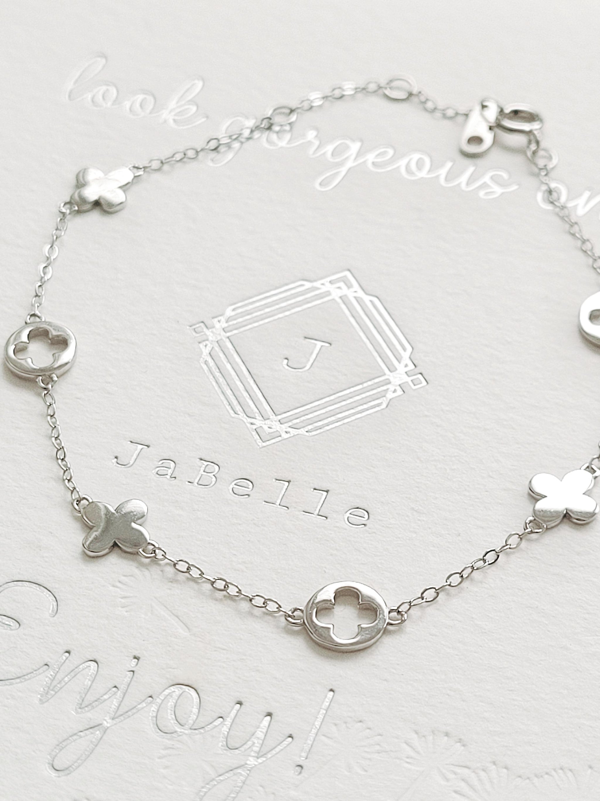A dainty sterling silver bracelet with clover charms.