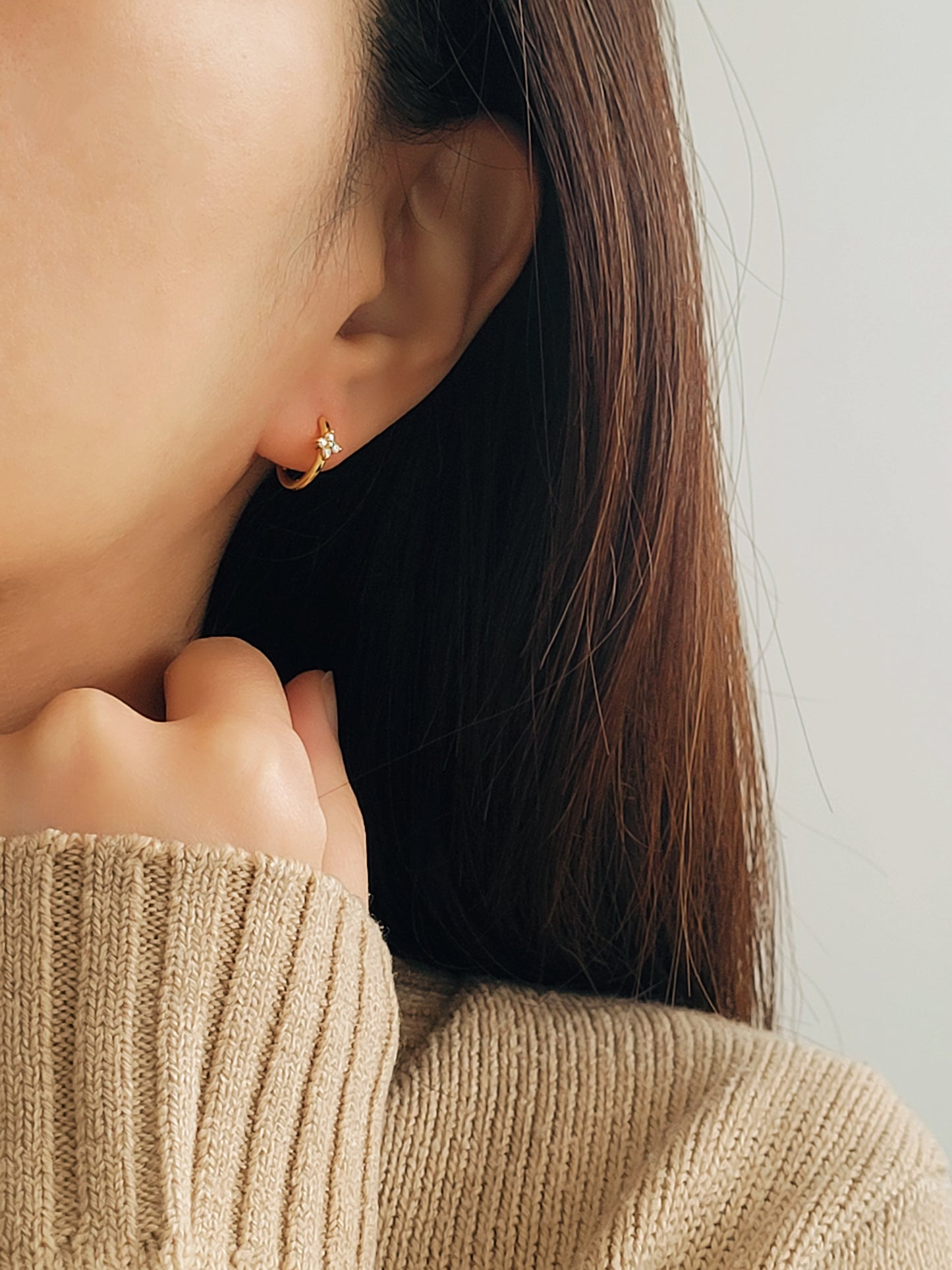 A girl wearing clover earrings with minimalist beige outfit.