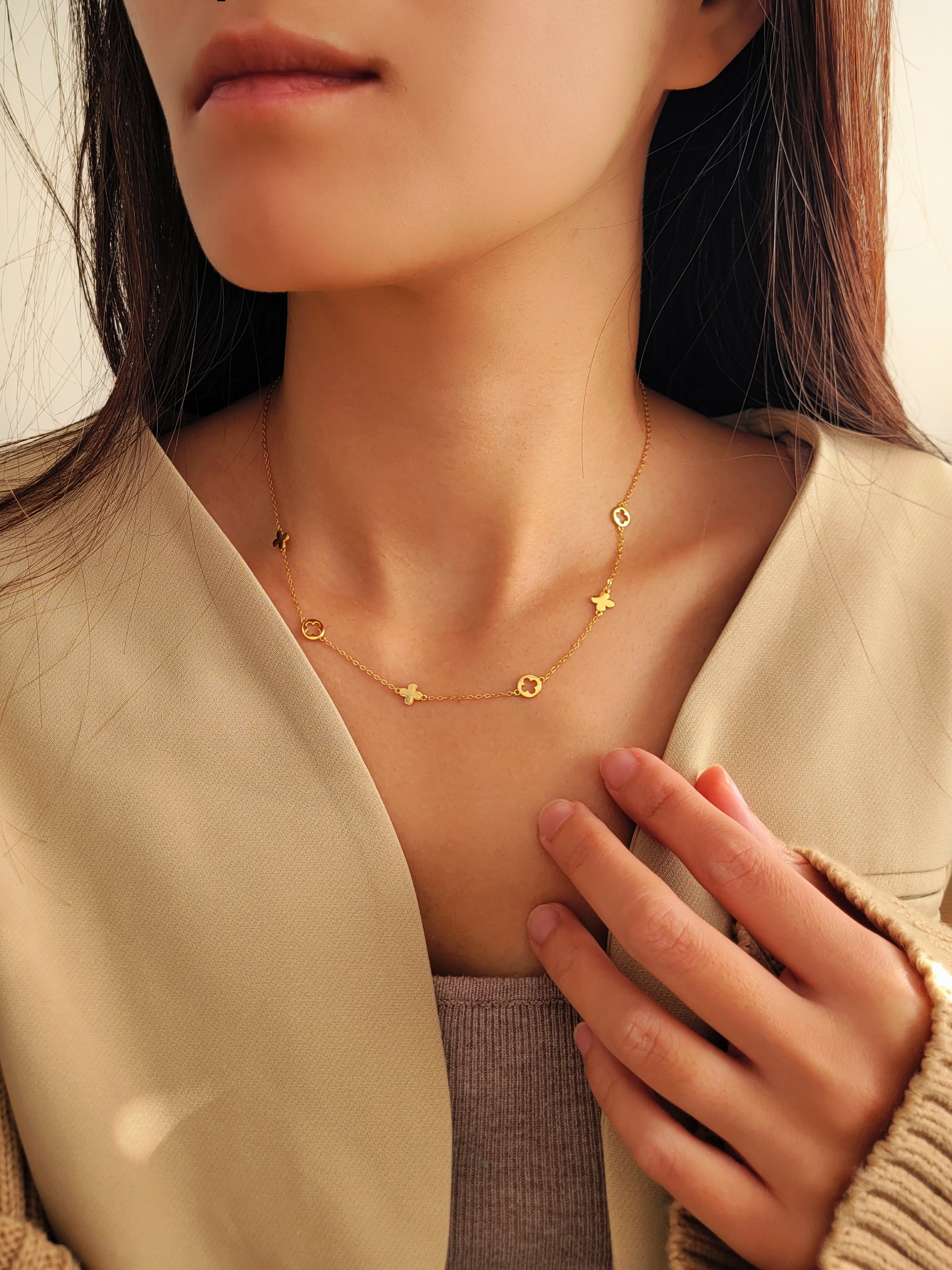 Close-up of a woman wearing a delicate gold necklace featuring clover charms.