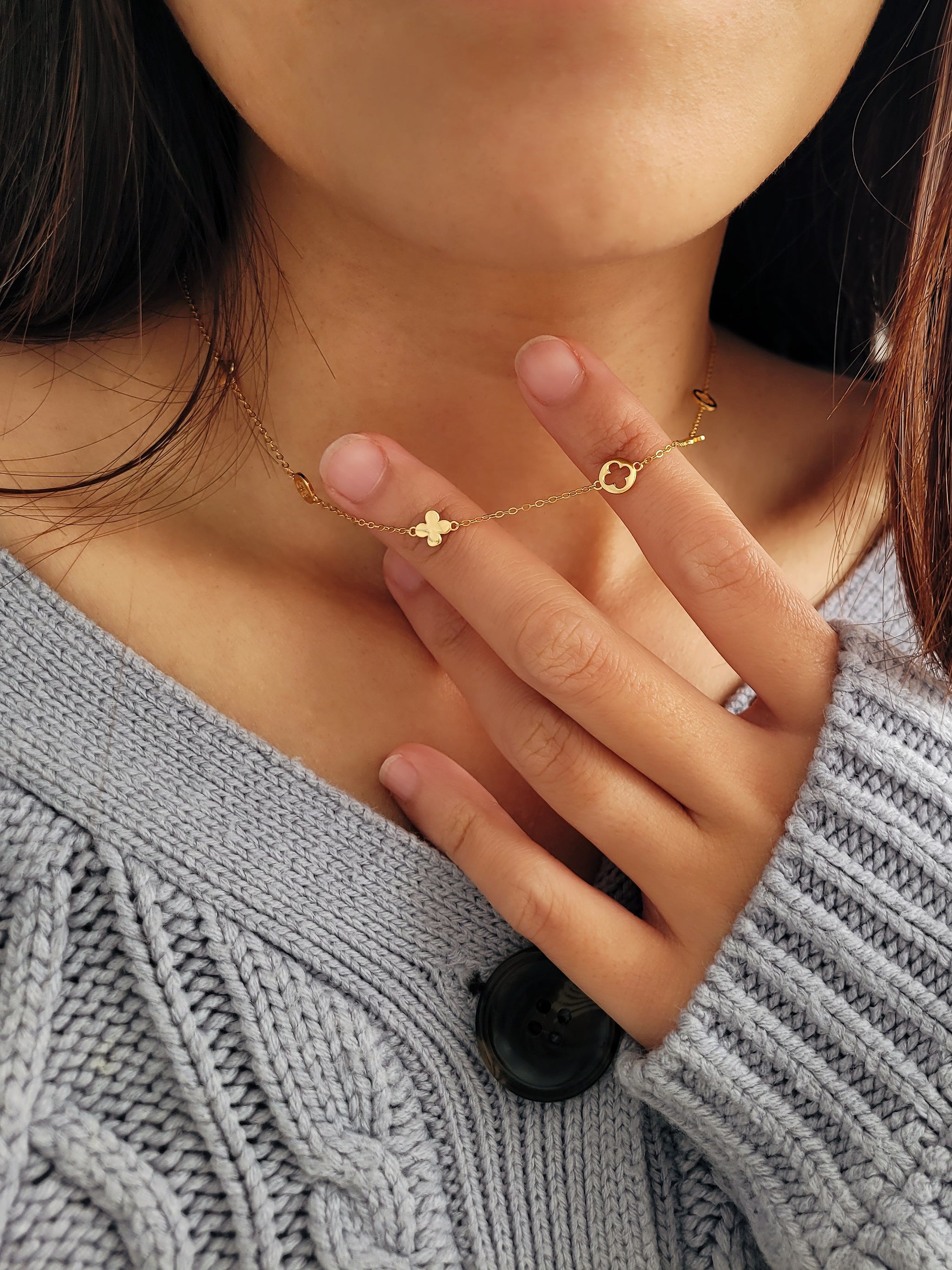 Close-up of a woman wearing a delicate gold necklace featuring clover coins.