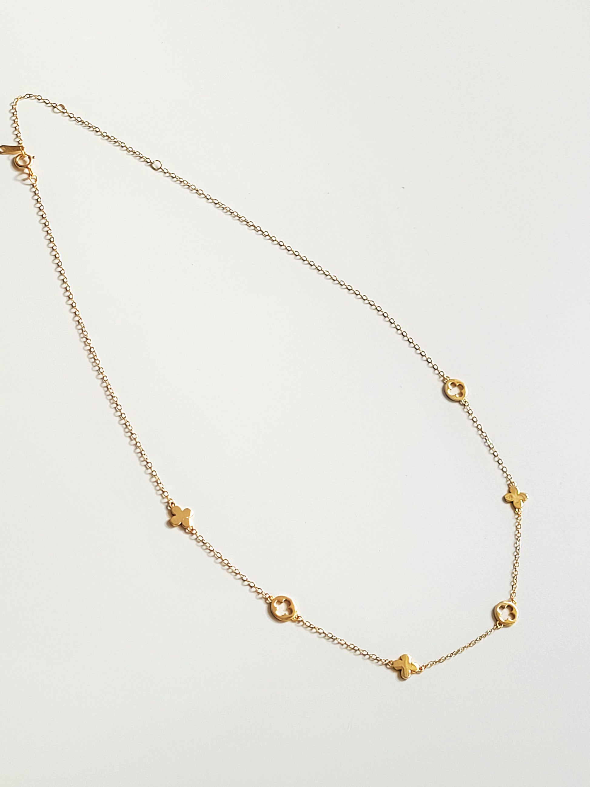 Gold necklace with star-shaped pendants on a light gray background