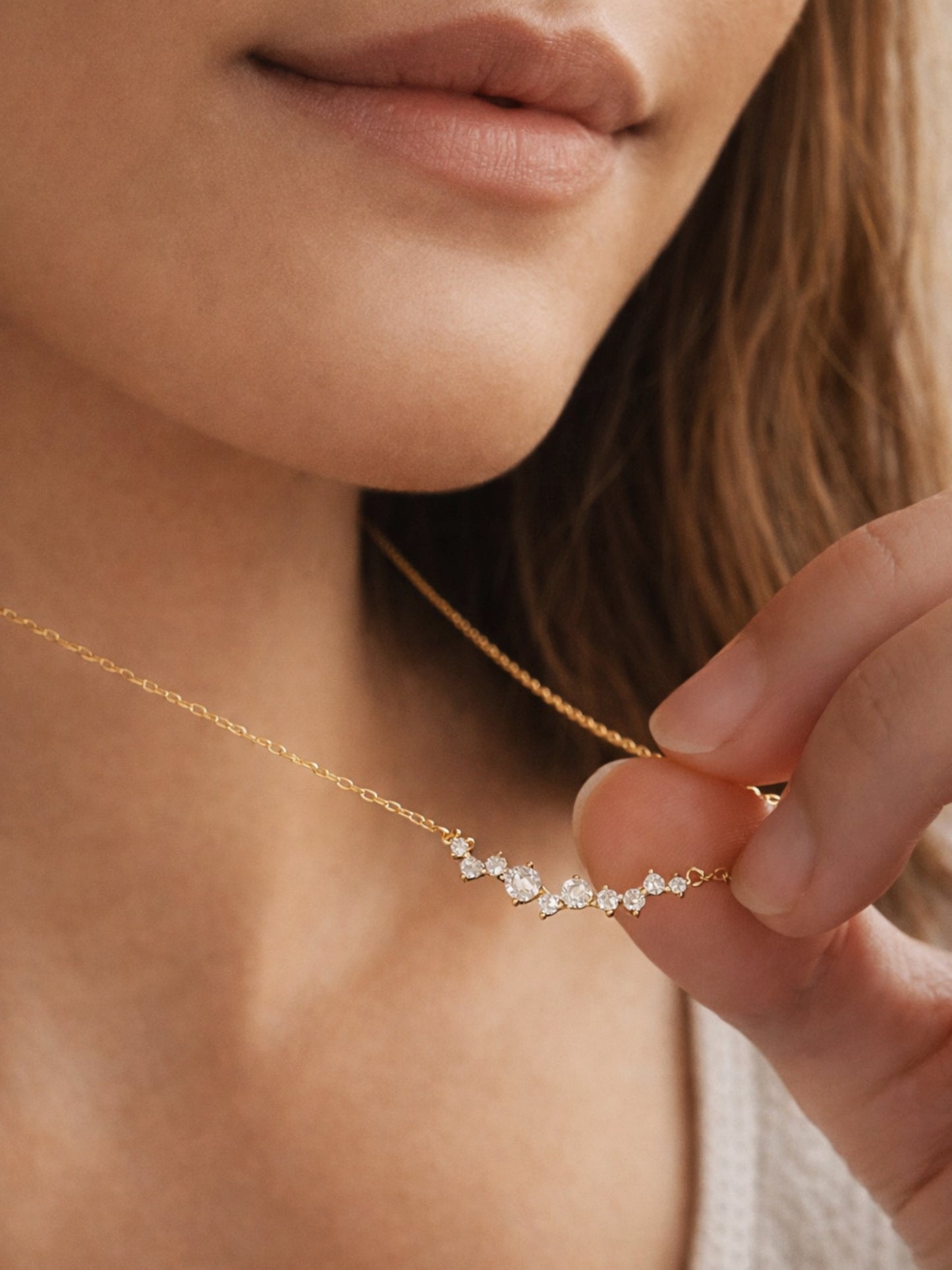 Close-up of a woman wearing a delicate gold necklace with small crystals.