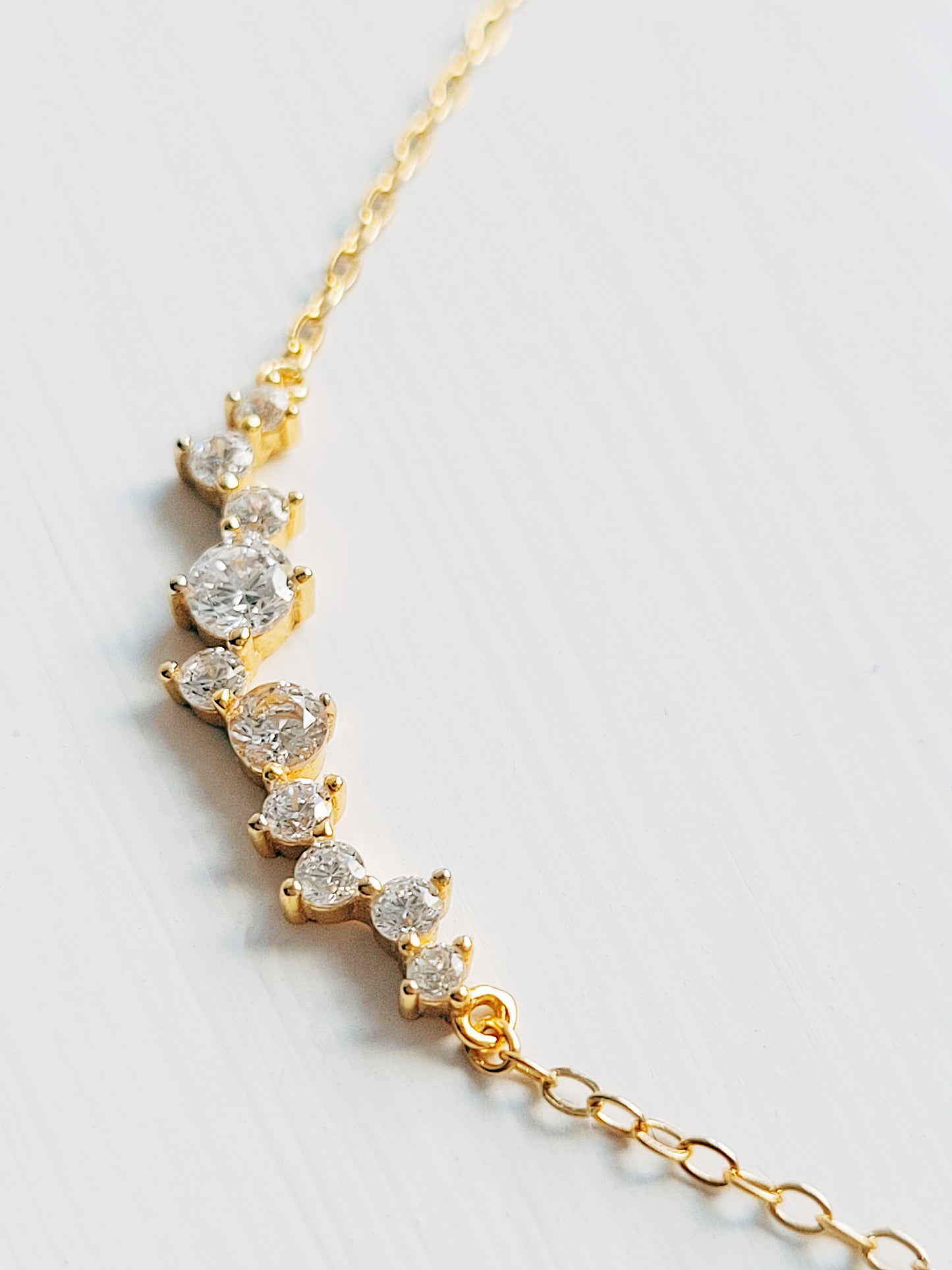 Close-up of a dainty gold necklace with curved cubic zirconia pendant, perfect anniversary gift for her.