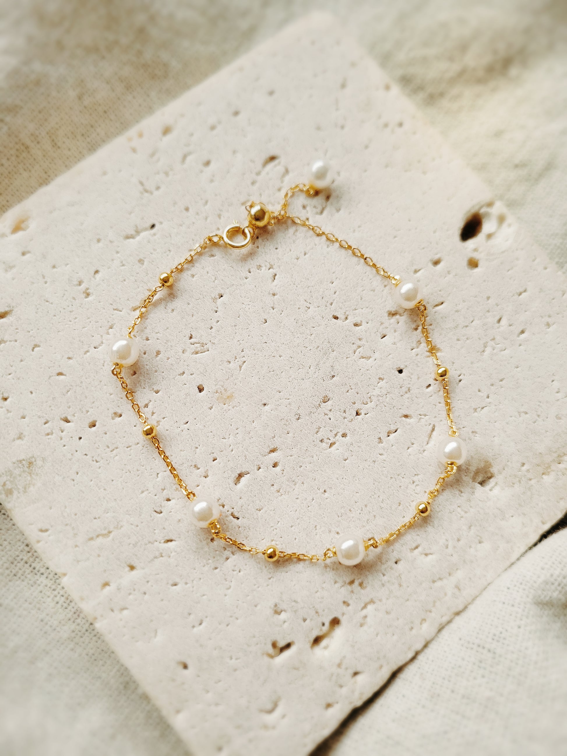 A delicate gold-plated sterling silver bracelet featuring pearls and an adjustable bead chain, ideal for weddings or gifting to loved ones.