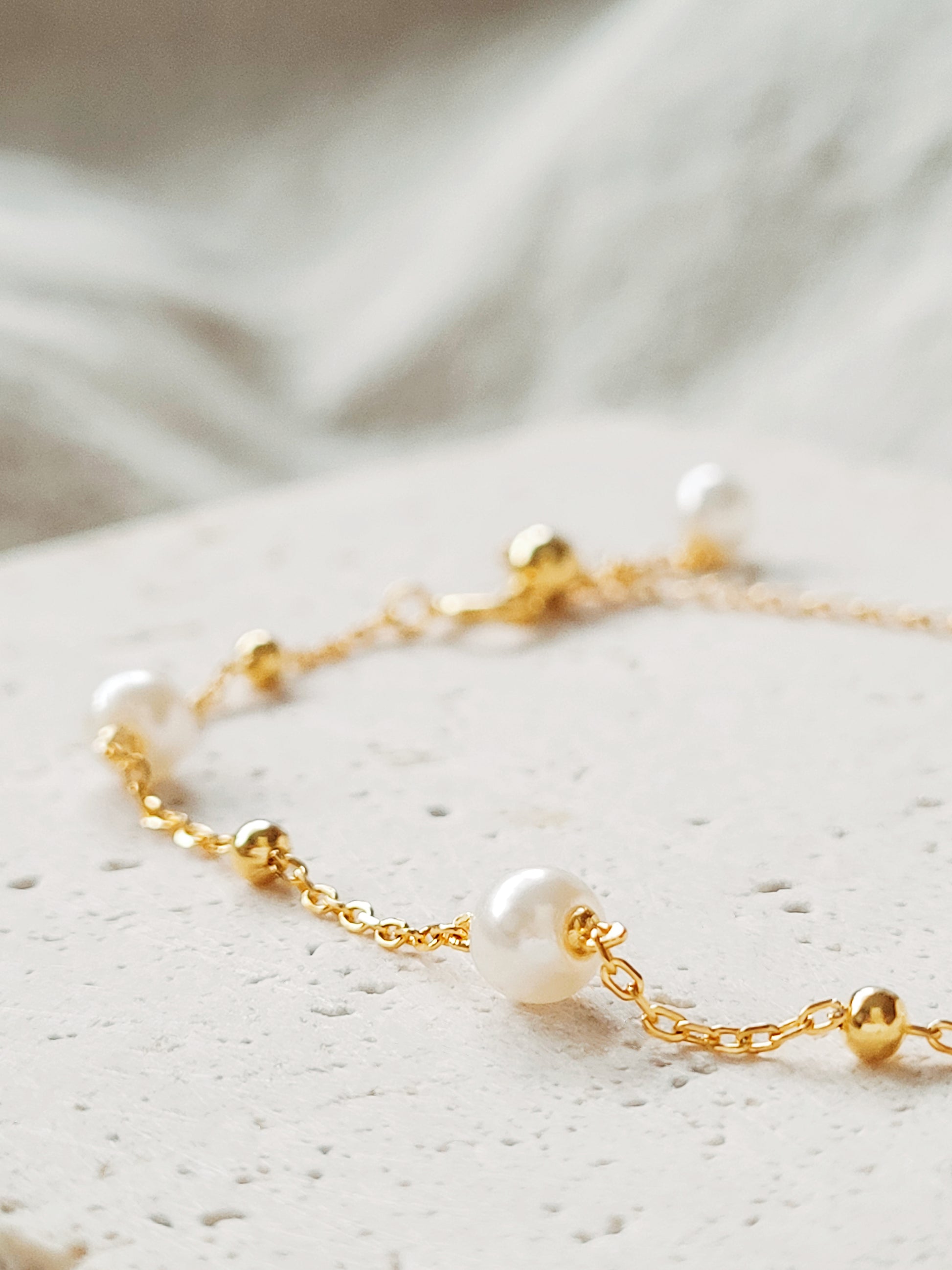 A delicate gold-plated sterling silver bracelet featuring pearls and an adjustable bead chain, ideal for weddings or gifting to loved ones.