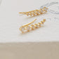 A pair of gold-plated sterling silver climber earrings adorned with cubic zirconia stones, displayed on a clean white surface.