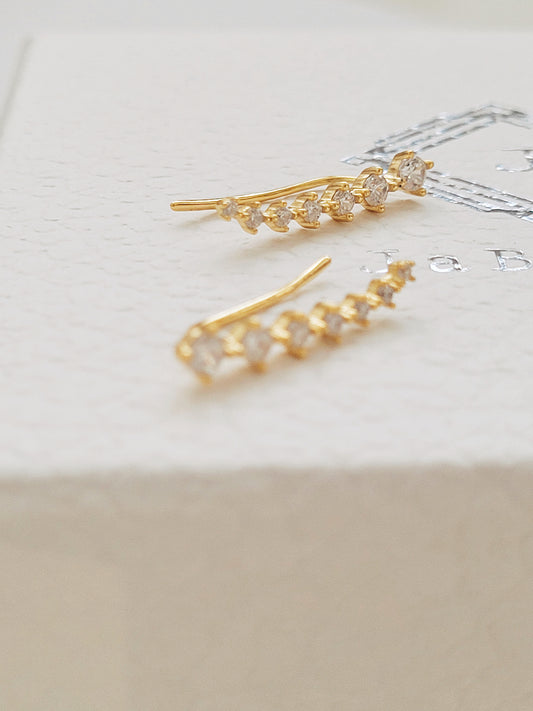 A pair of gold-plated sterling silver climber earrings adorned with cubic zirconia stones, displayed on a clean white surface.