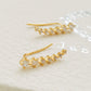 A pair of gold-plated sterling silver climber earrings adorned with cubic zirconia stones, displayed on a clean white surface.